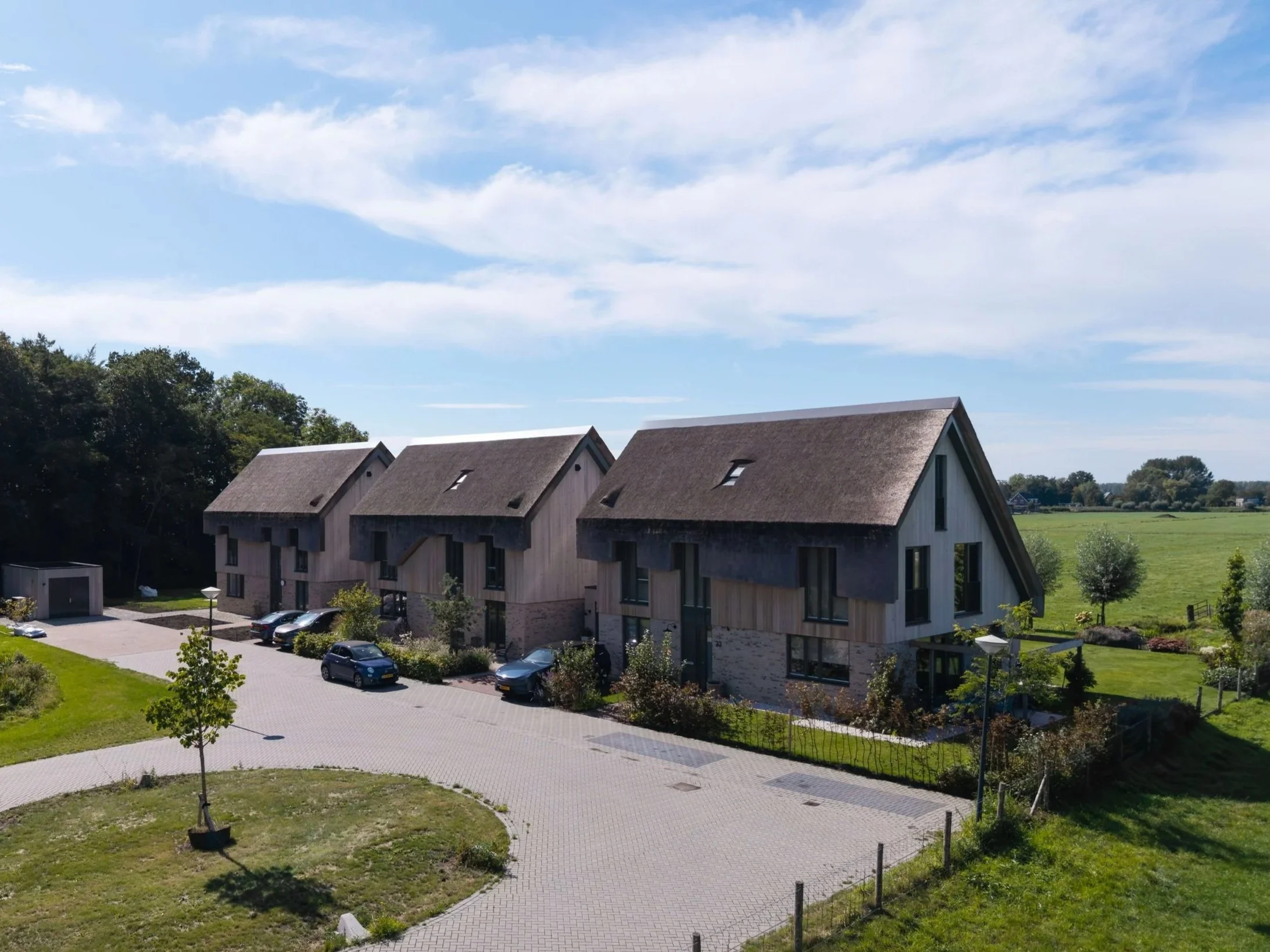 Drie nieuwbouwwoningen met rieten daken en houten gevels in een groene omgeving in Nederhorst den Berg als voorbeeld van landelijke nieuwbouw woningbouw architectuur.