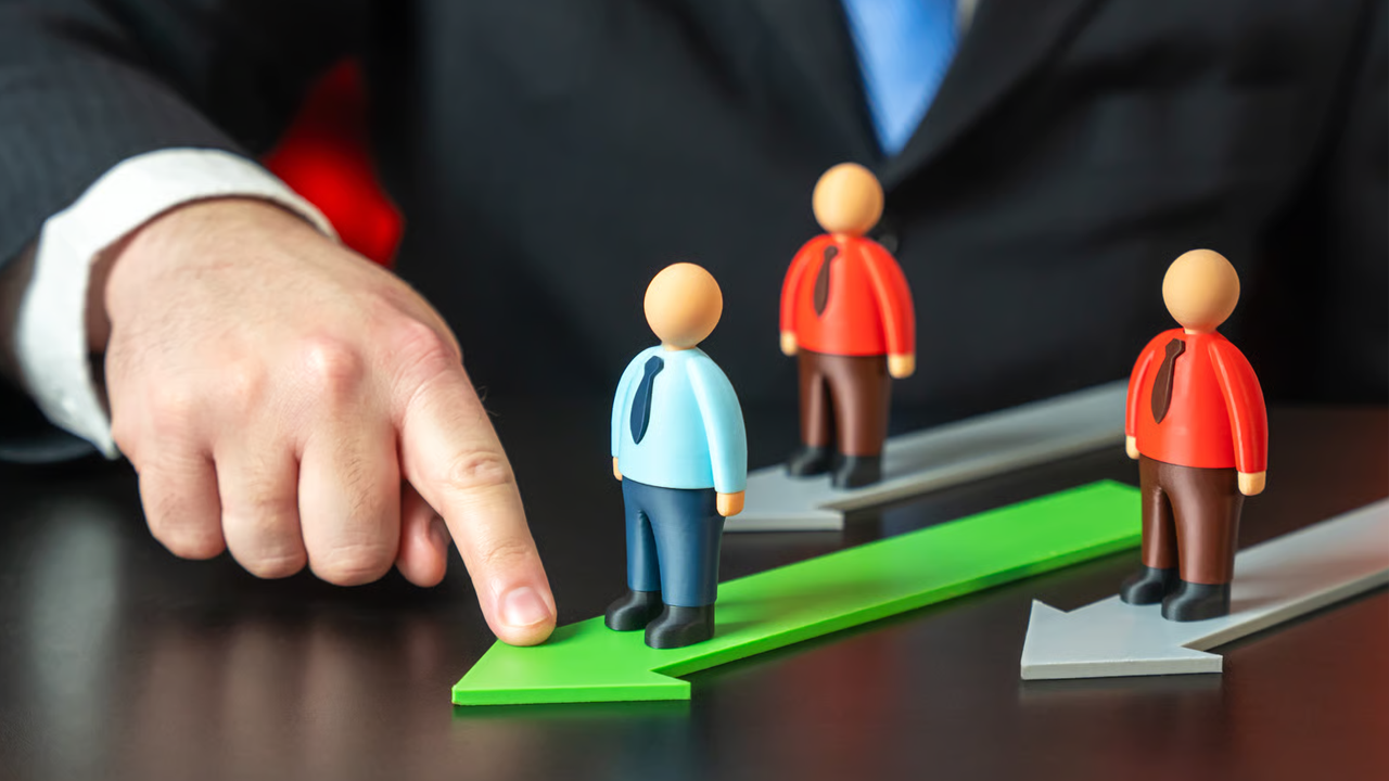 Hand guiding a business figure on a green arrow toward clear team goals