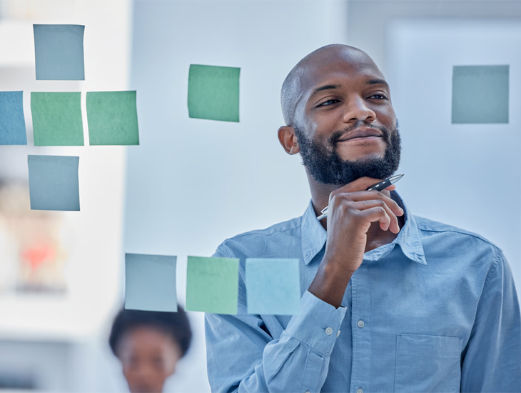 A thoughtful businessman reviewing business insights on a sticky note wall.