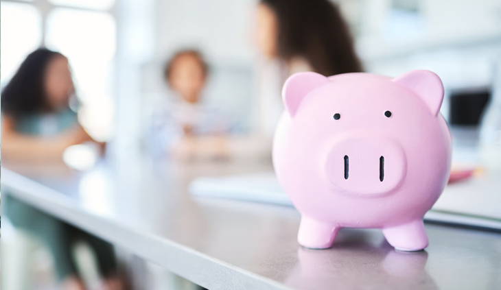 A pink piggy bank sits on a table to show financial savings for families.