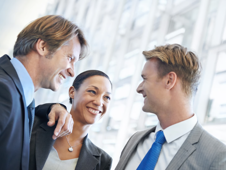 Three smiling business professionals collaborating in a bright modern office.