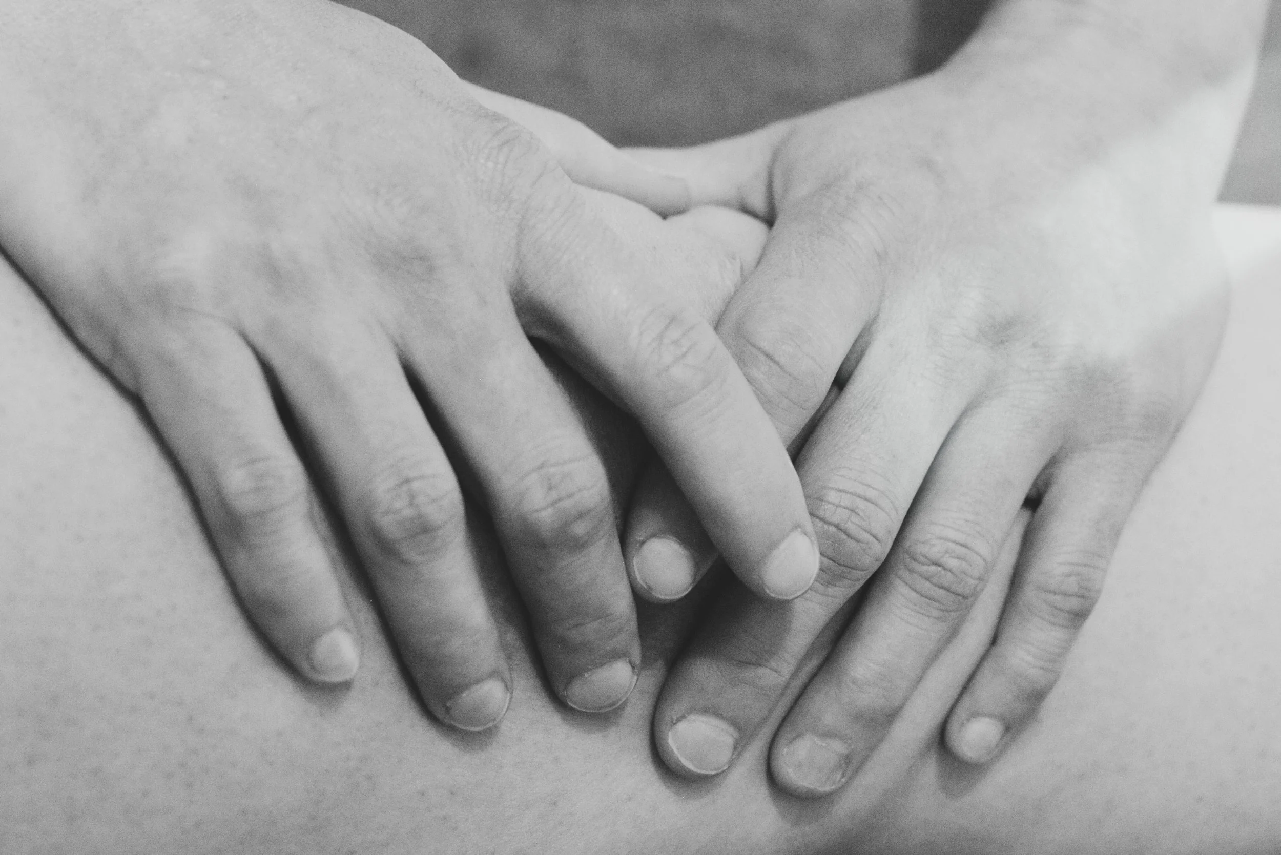 Close-up of two hands gently holding each other, black and white photo.