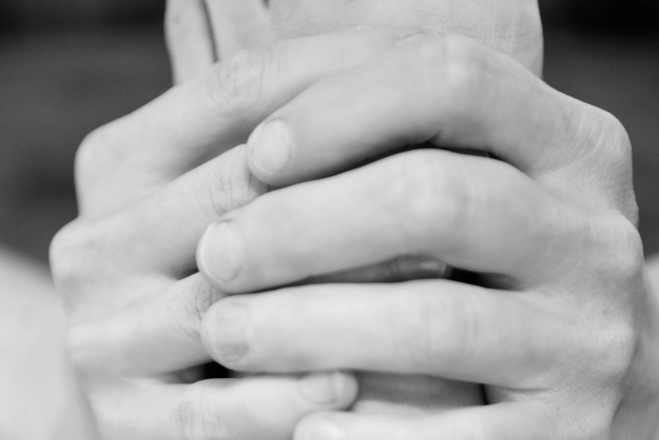 Close-up of two hands clasped together, black and white photo.