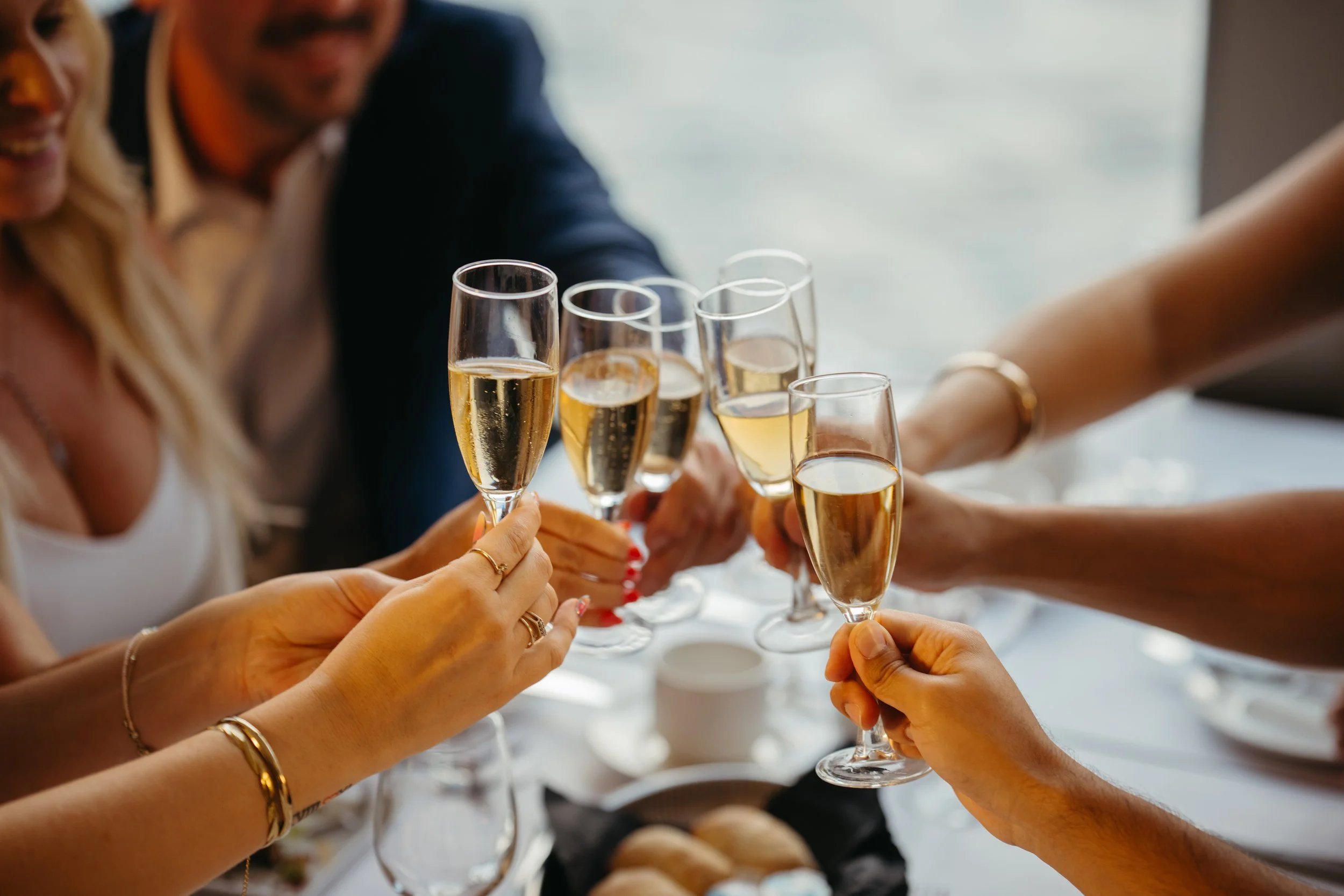 Several people are clinking champagne flutes filled with champagne during a celebration or gathering.