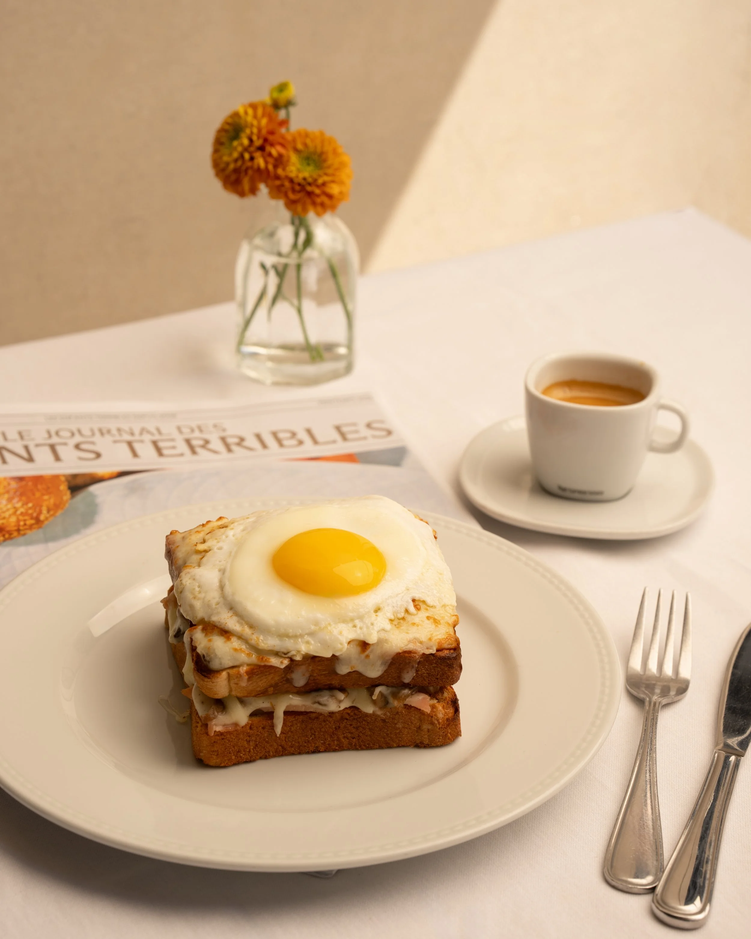 A slice of bread topped with melted cheese and a sunny-side-up egg on a white plate