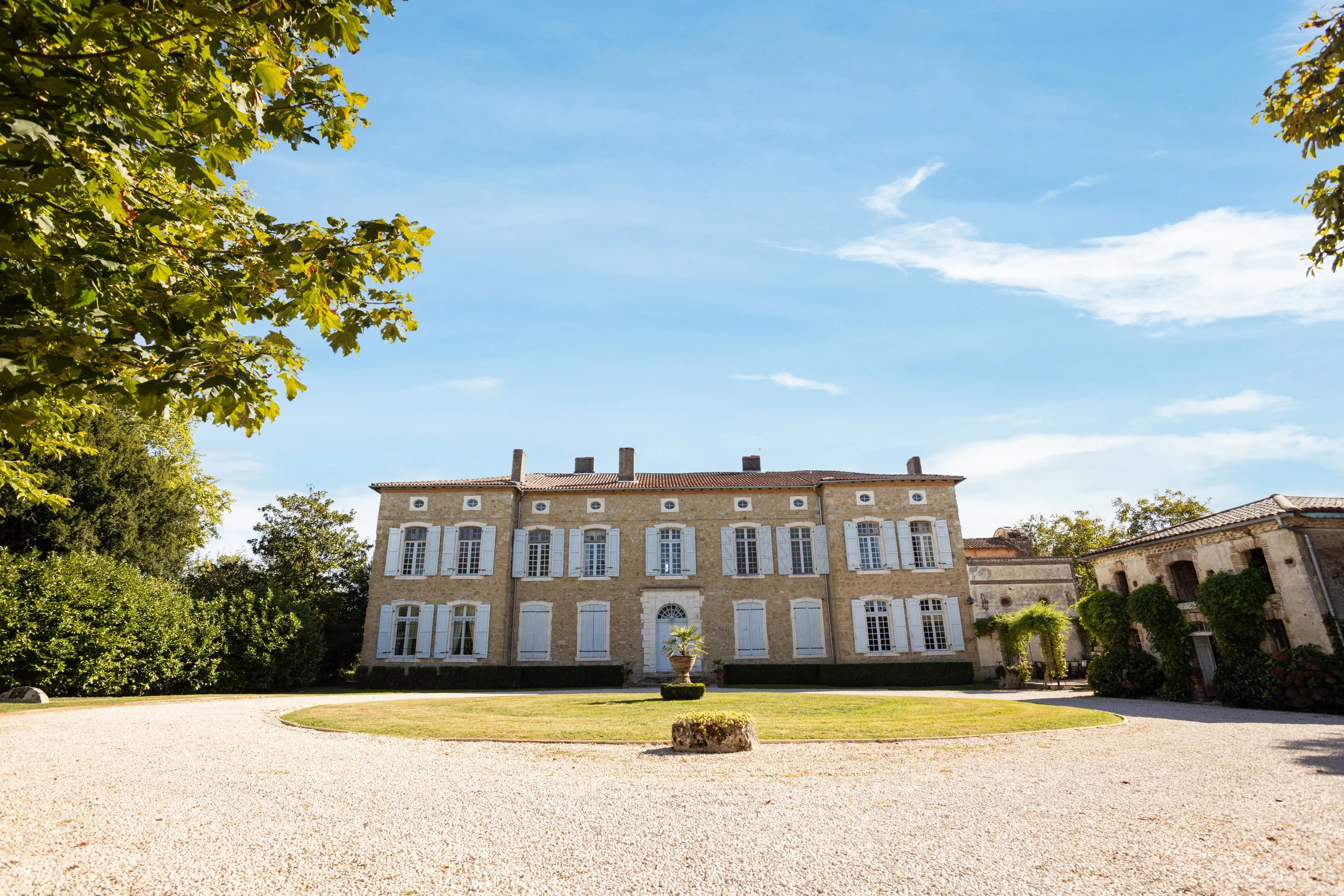 Grand stone chateau with shuttered windows and gravel driveway, a Curated Property holiday let in France.