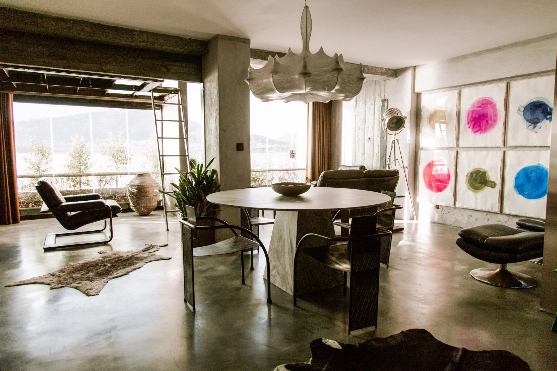 A handleless stainless steel kitchen runs the length of the room, paired with a dark marble splashback and countertop. The polished concrete floor flows through into an open-plan dining and living space, with large windows letting in natural light be