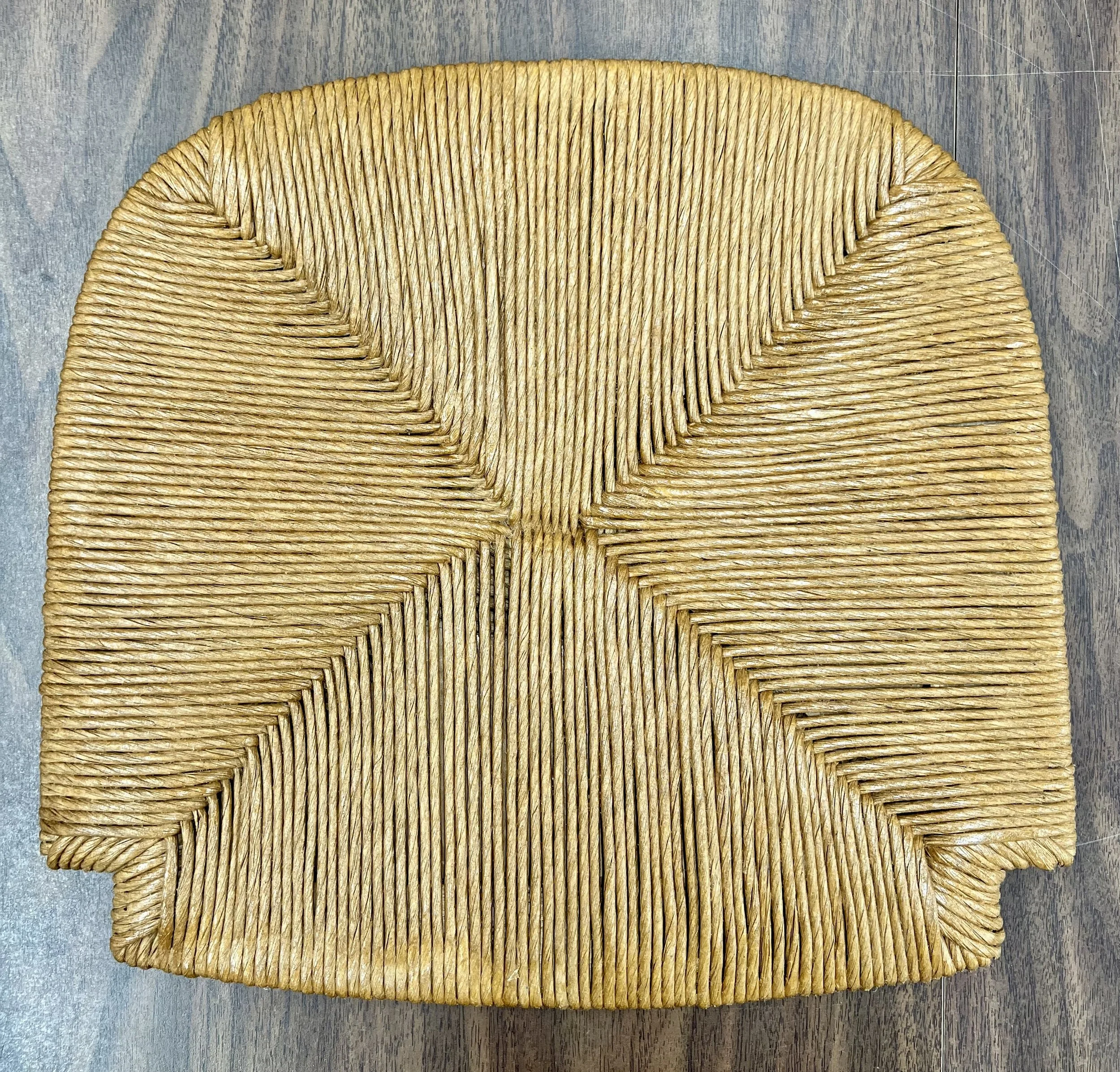 Wicker chair with a curved design placed on a wooden floor.