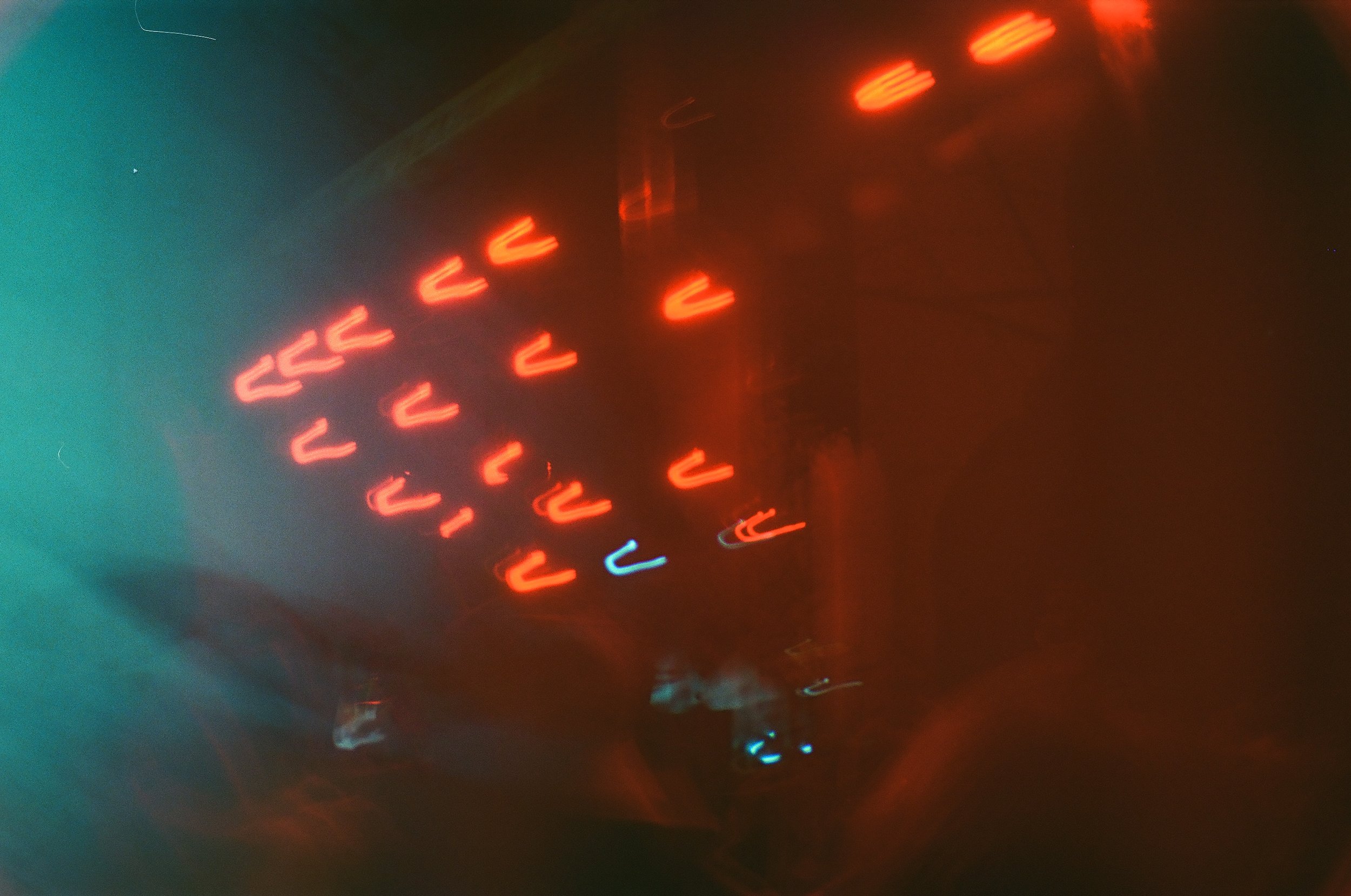 A blurry photo of red and blue neon lights, possibly from a digital sign or display, with a dark background.
