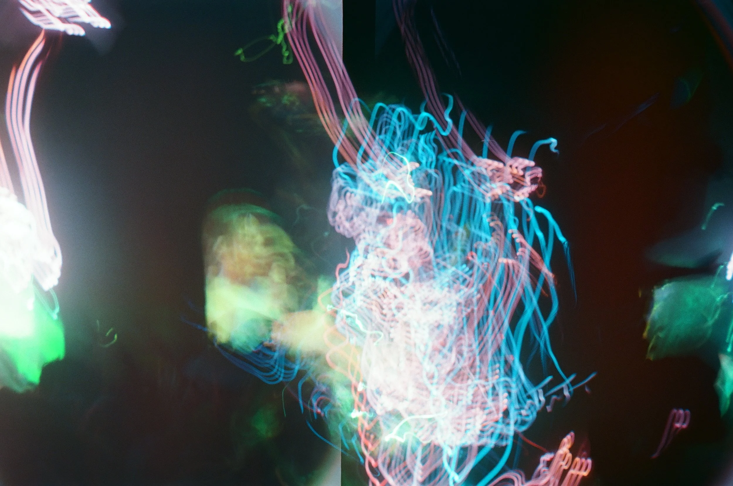 Colorful neon light trails creating abstract, swirling patterns against a dark background.