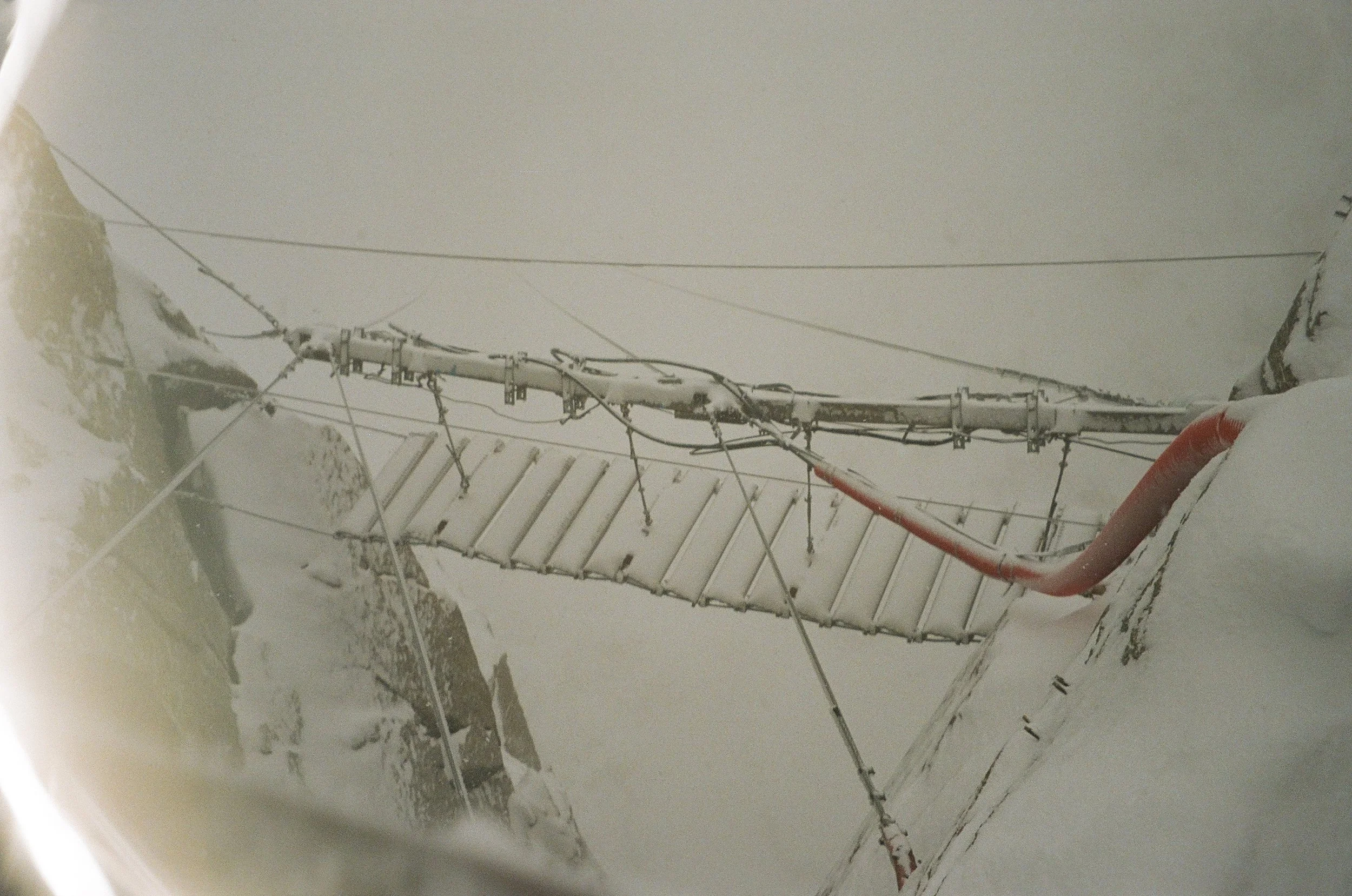Close-up of snow-covered electrical poles and wires in a wintry landscape.