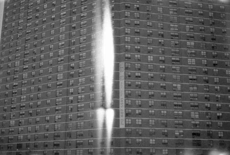 Reflected image of a high-rise building in a shiny metallic surface.