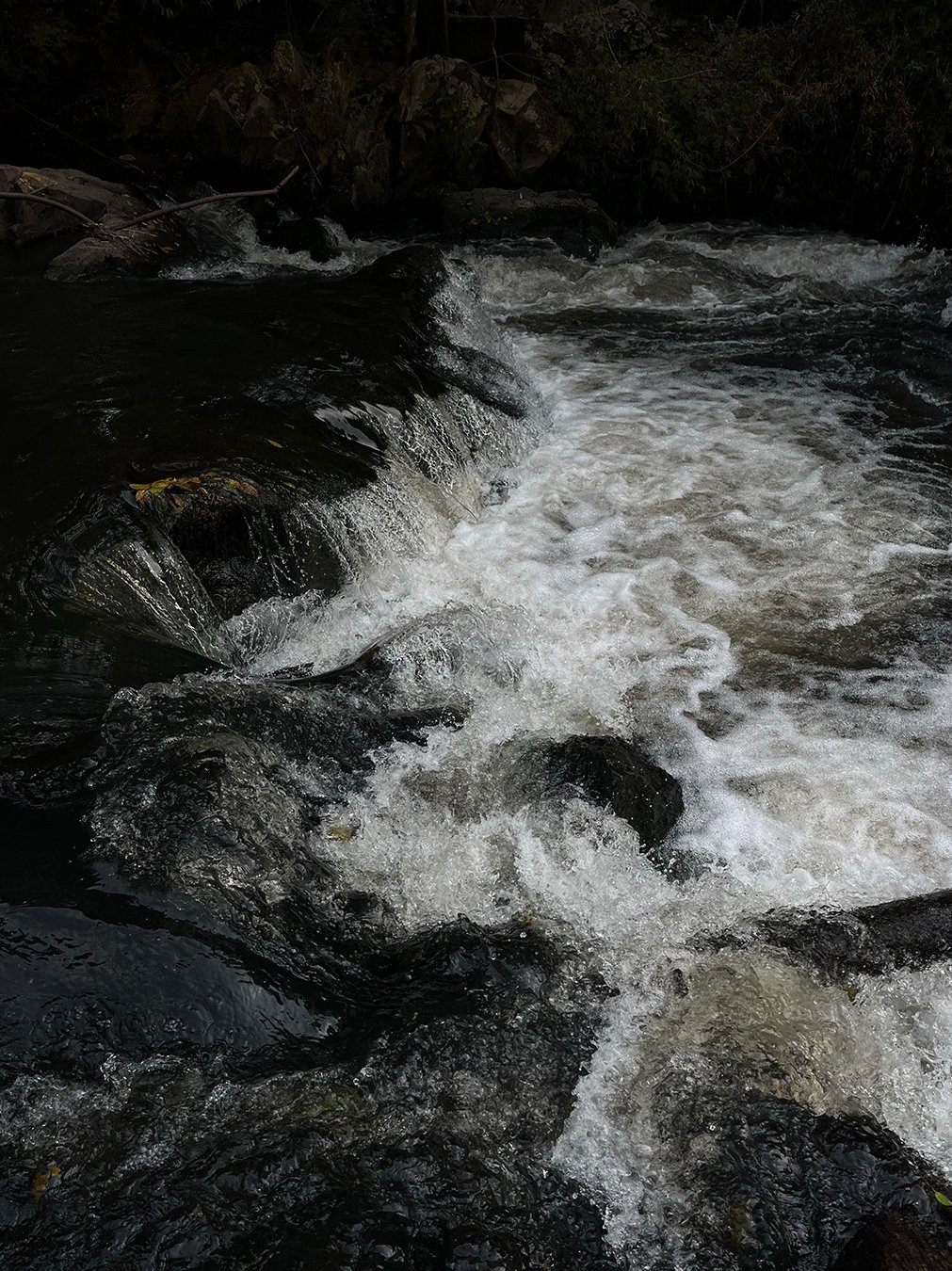 Flowing water over dark rocks, symbolizing the peace and transformation that come from God’s presence
