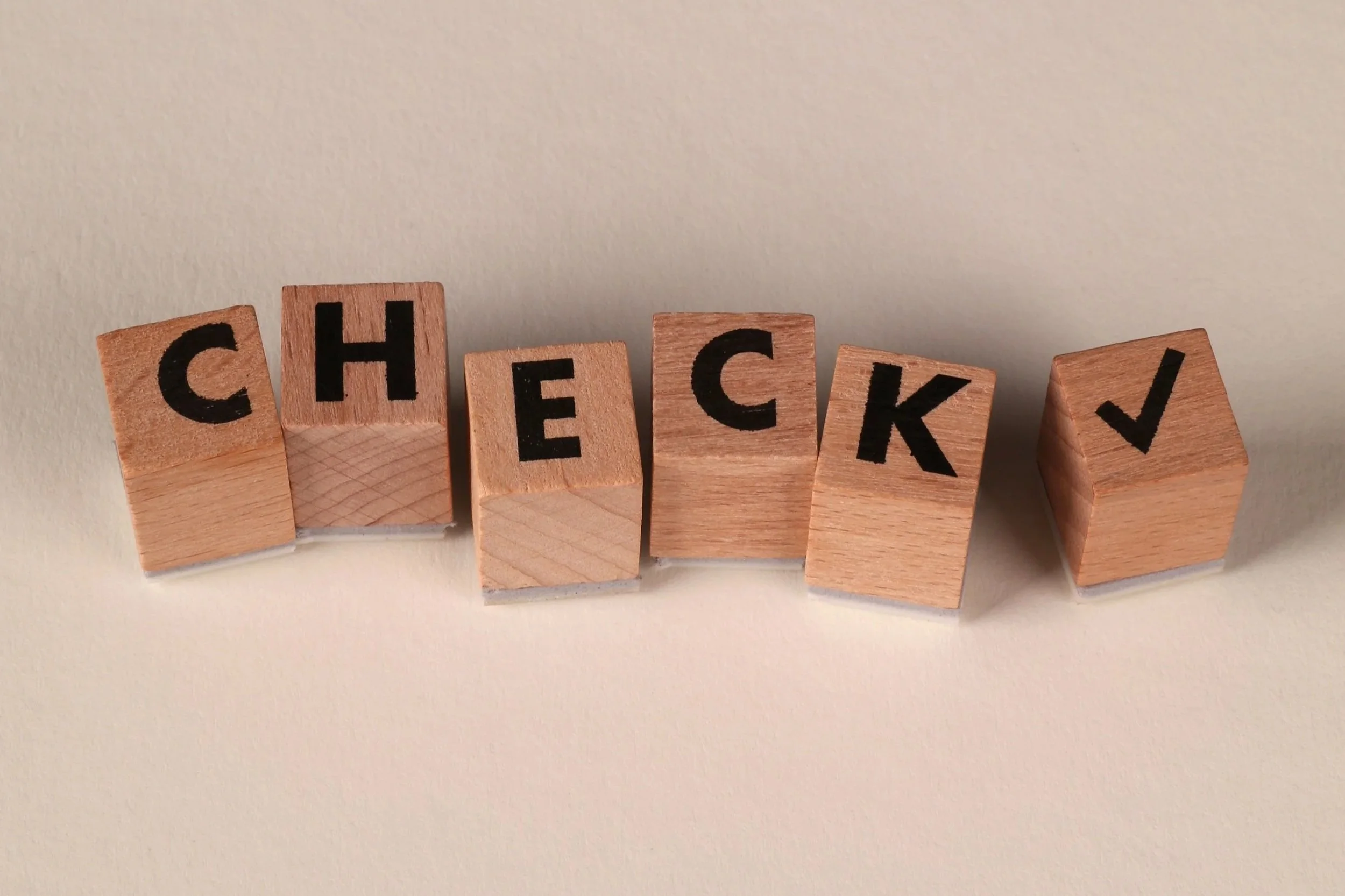 Holzblöcke mit dem Wort „CHECK“ und Häkchen als Symbol für klare Standards und Checklisten in Bar-Abläufen.