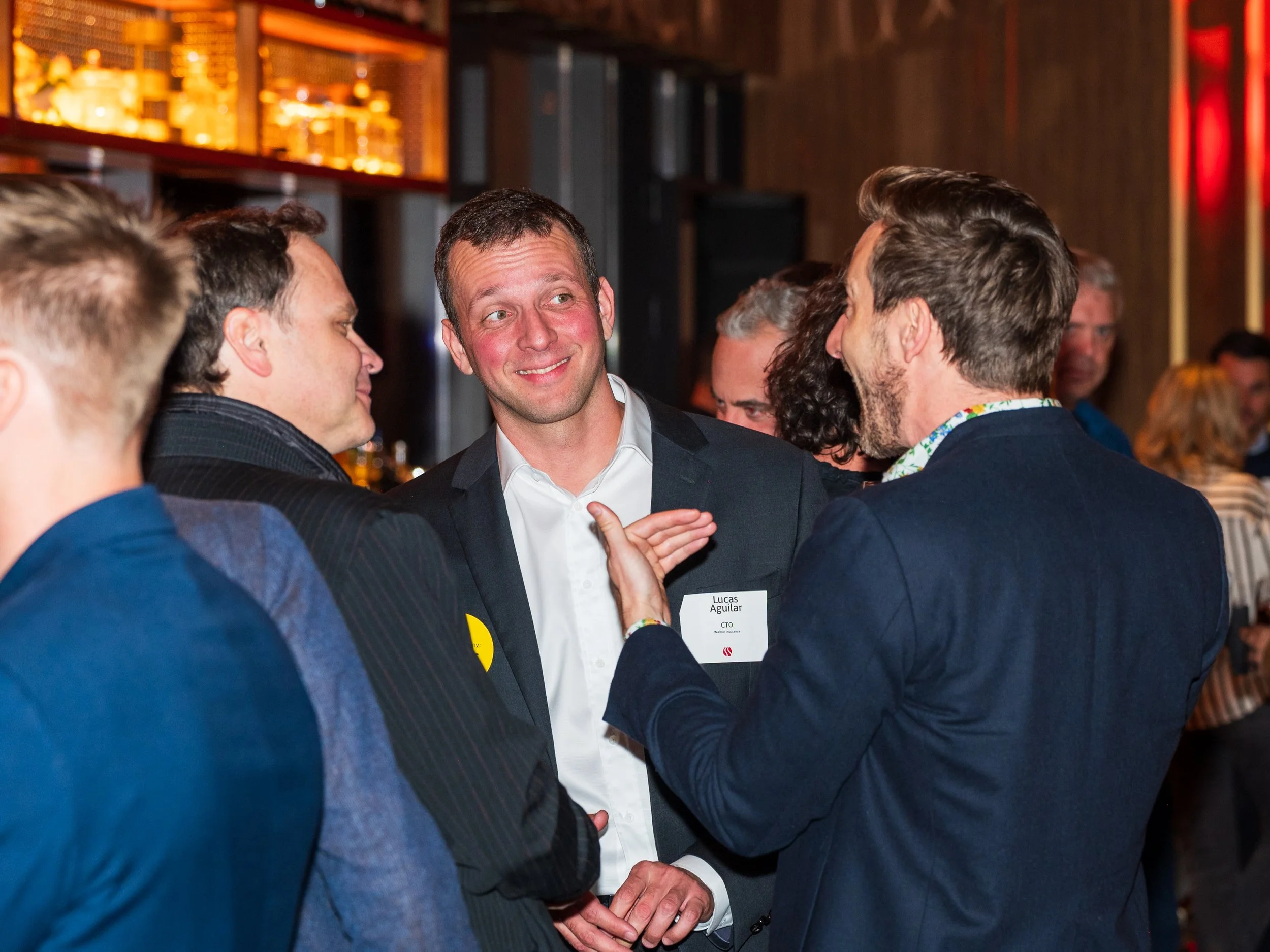Group of men in business attire having a conversation at a social event or networking reception.