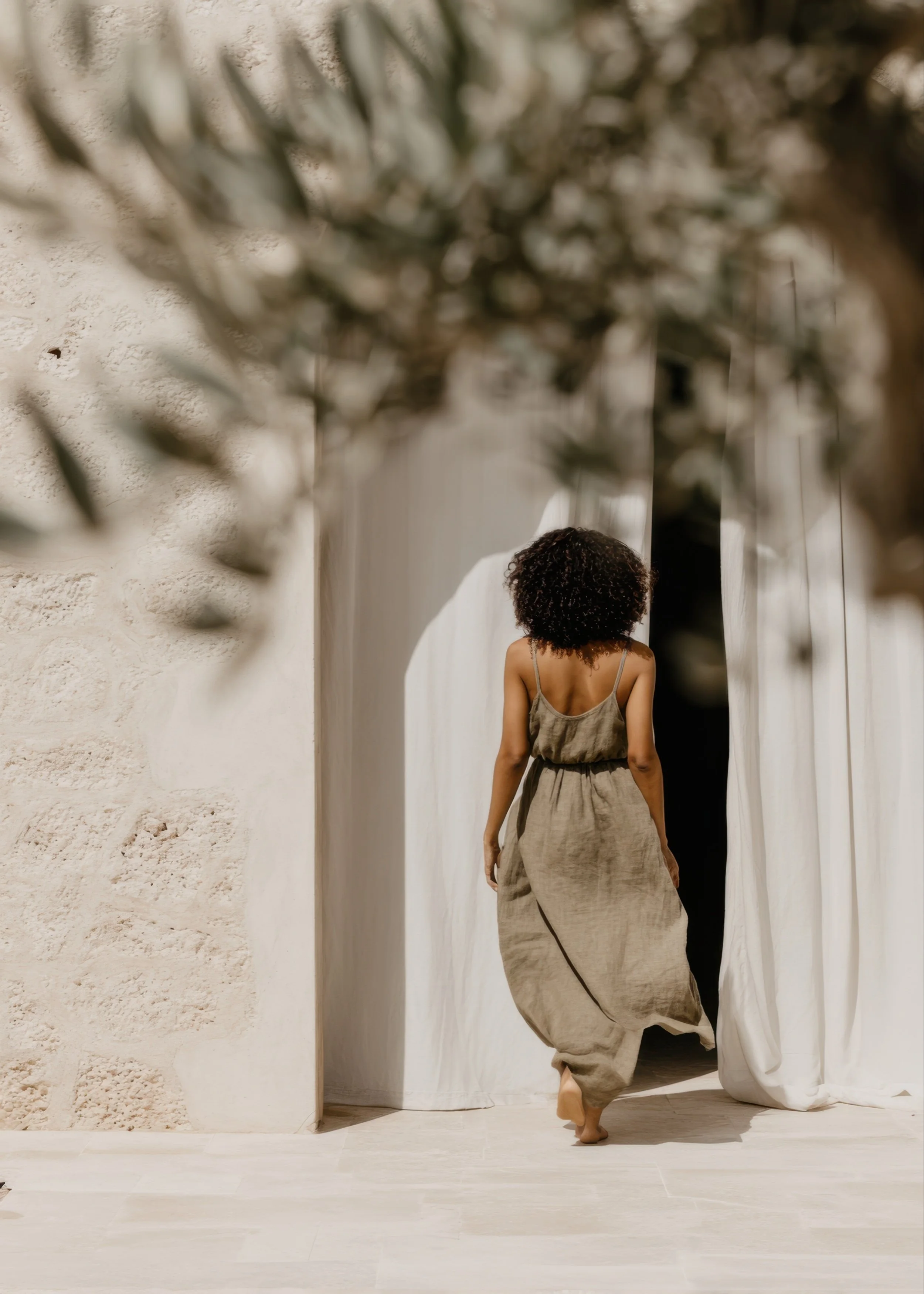 Woman walking into a calm, light-filled space with natural textures and warm tones