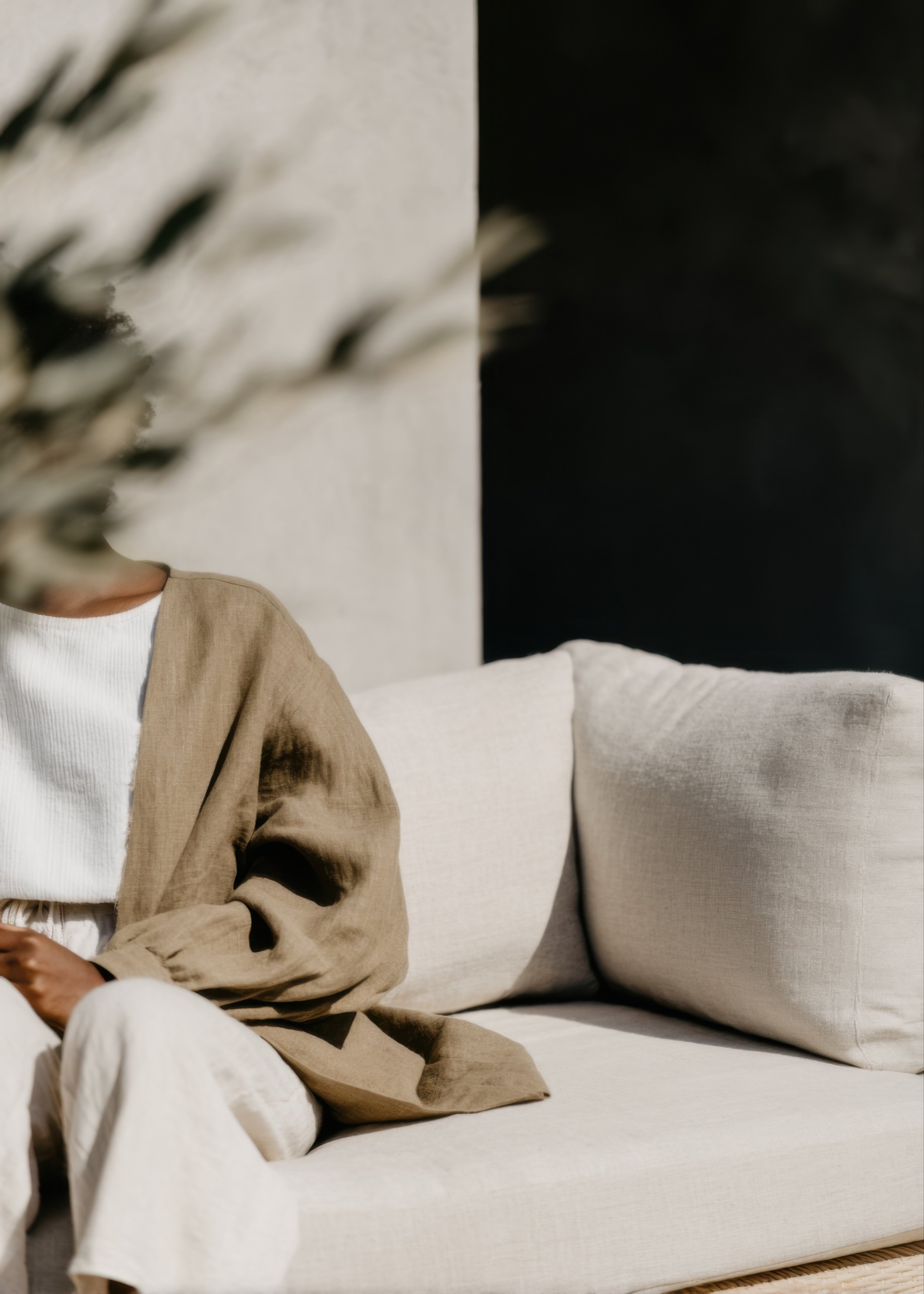 Person sitting on a light-colored couch in a calm, sunlit therapy space