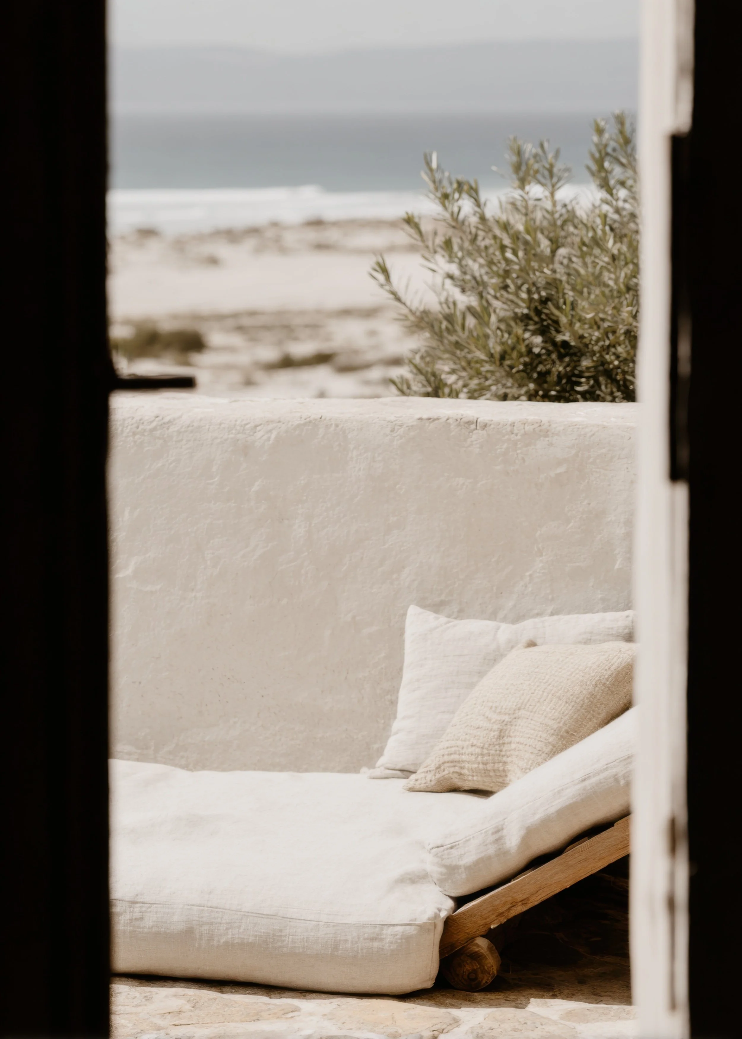 Sunlit outdoor lounge with neutral seating and coastal surroundings