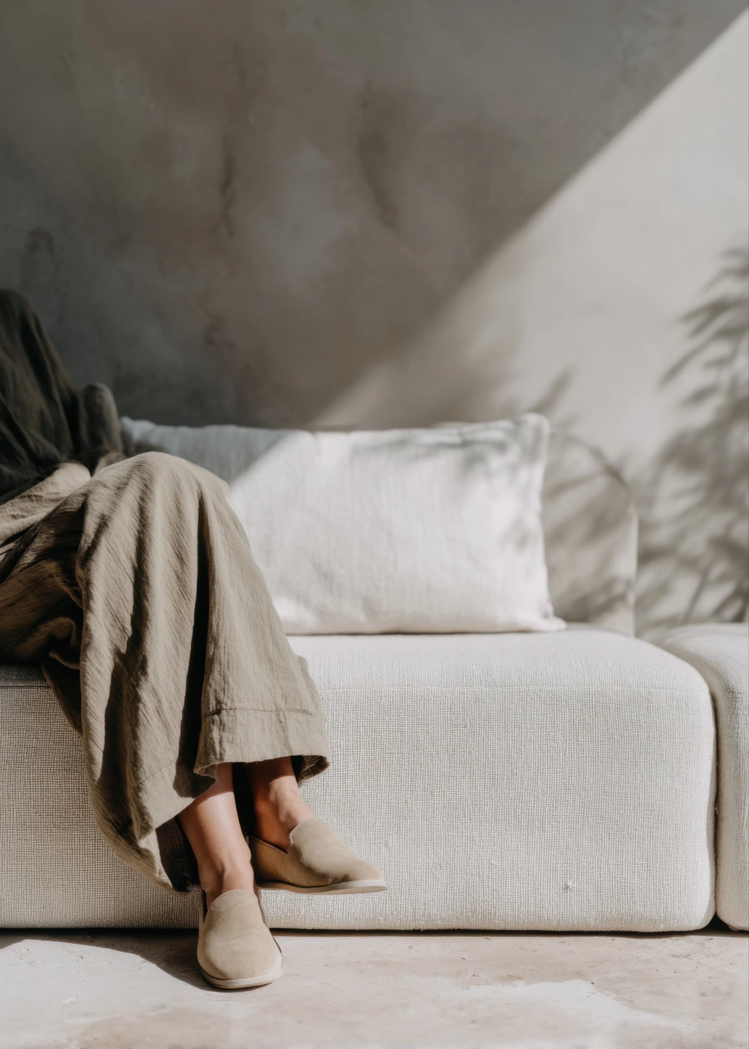 Calming therapy office scene with person seated on a neutral sofa in natural light