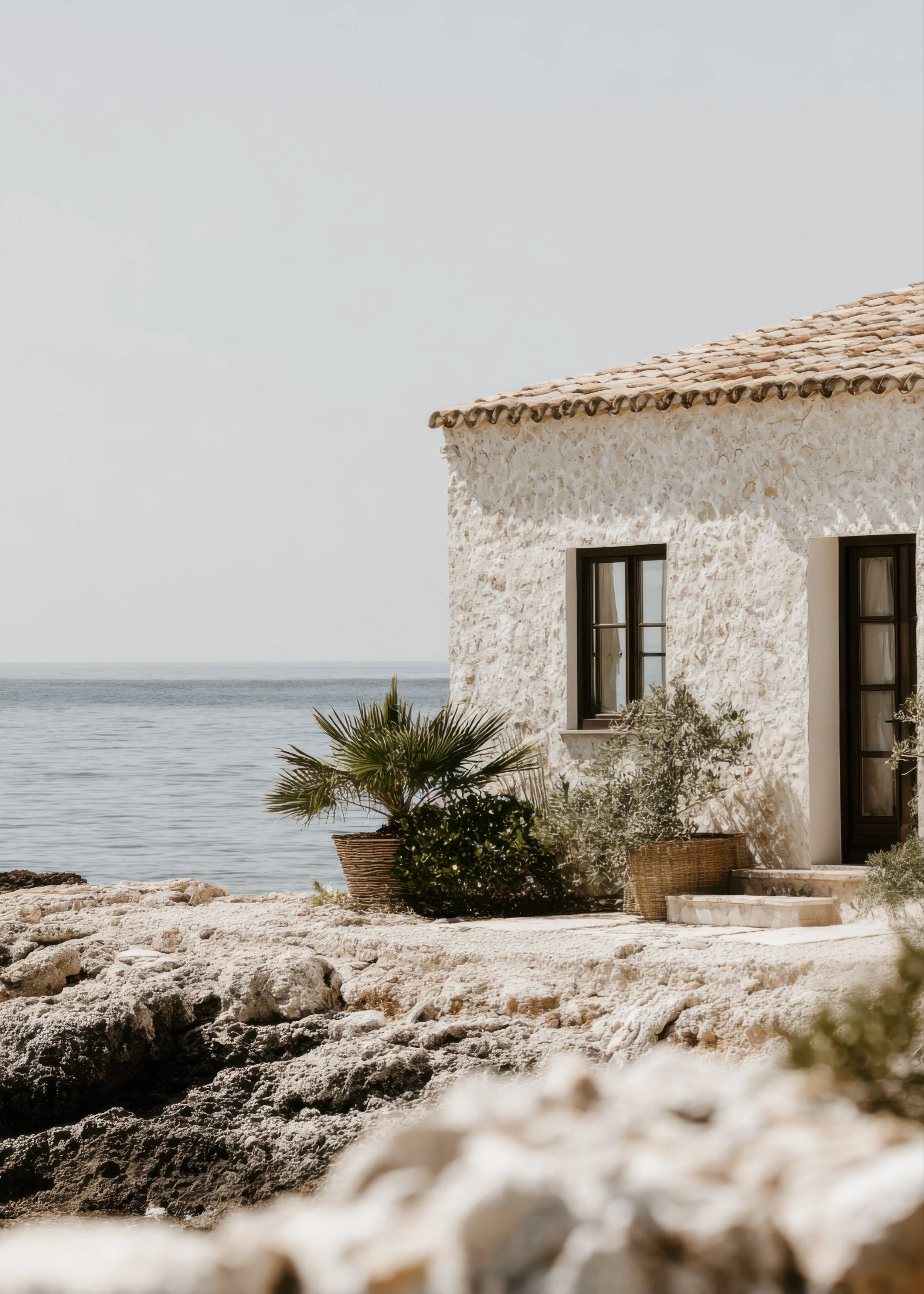 Sunlit building overlooking the ocean with natural stone and greenery