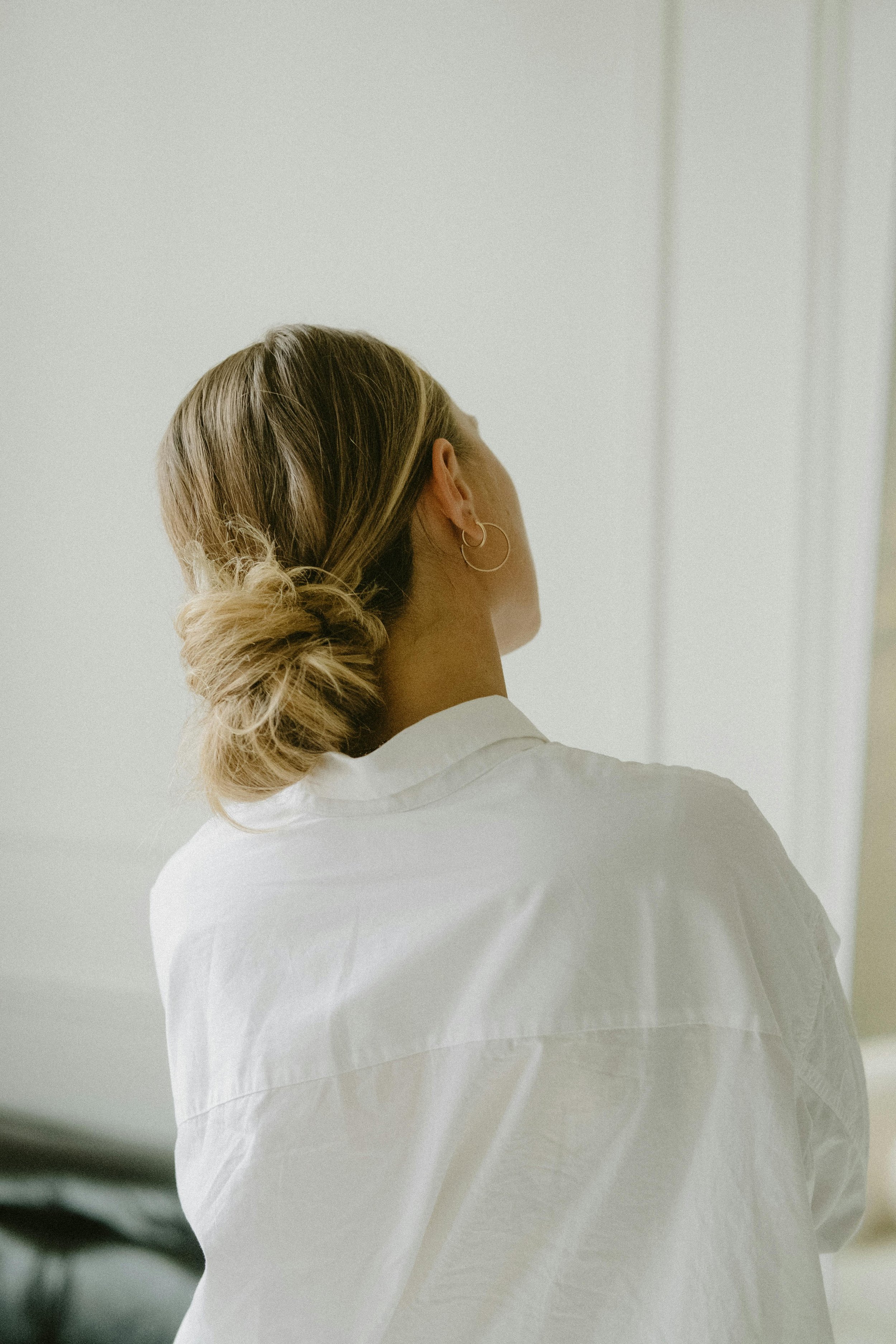 Adult woman with hair in a low bun wearing a white shirt, seated in a calm setting, featured on a webpage about adult therapy in Redondo Beach and the South Bay.