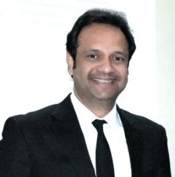 Smiling person in a suit and tie, with blurred background