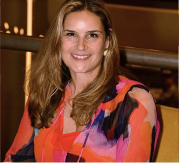 Person with long hair wearing a colorful blouse and smiling
