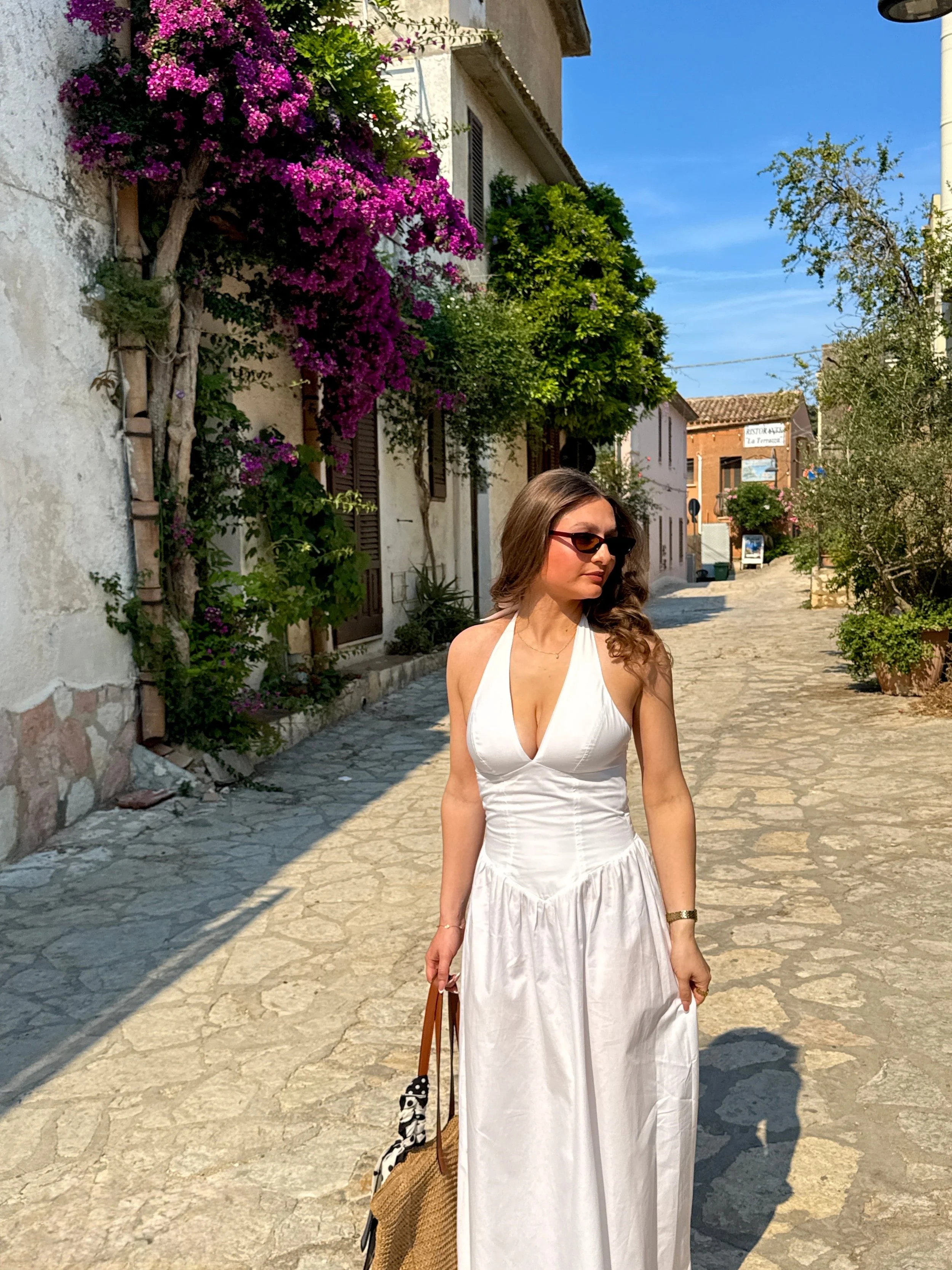 A woman in a flowing white dress stands gracefully in front of a charming house