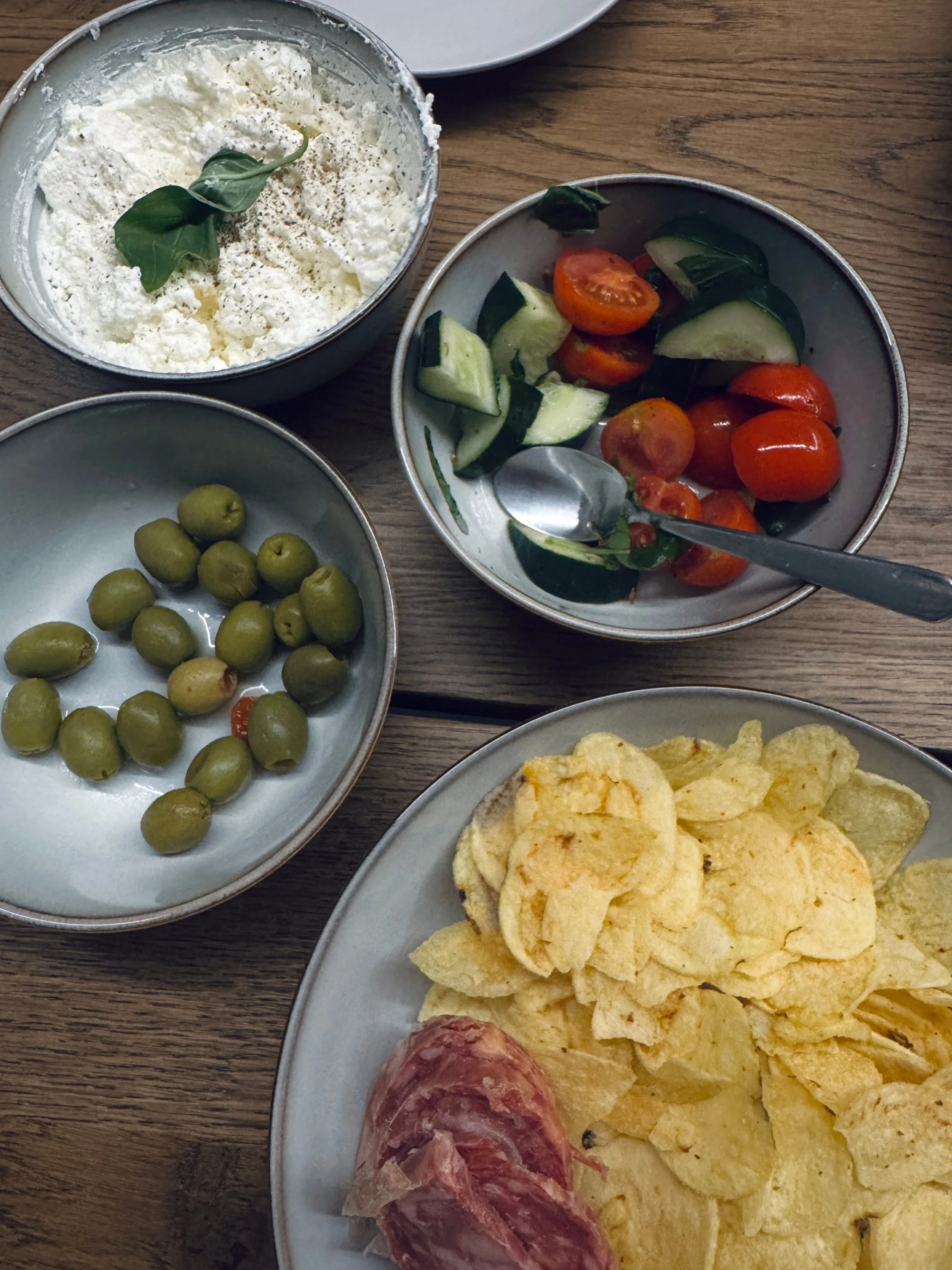 A vibrant table display featuring various bowls of food alongside plates filled with crunchy chips, perfect for sharing.