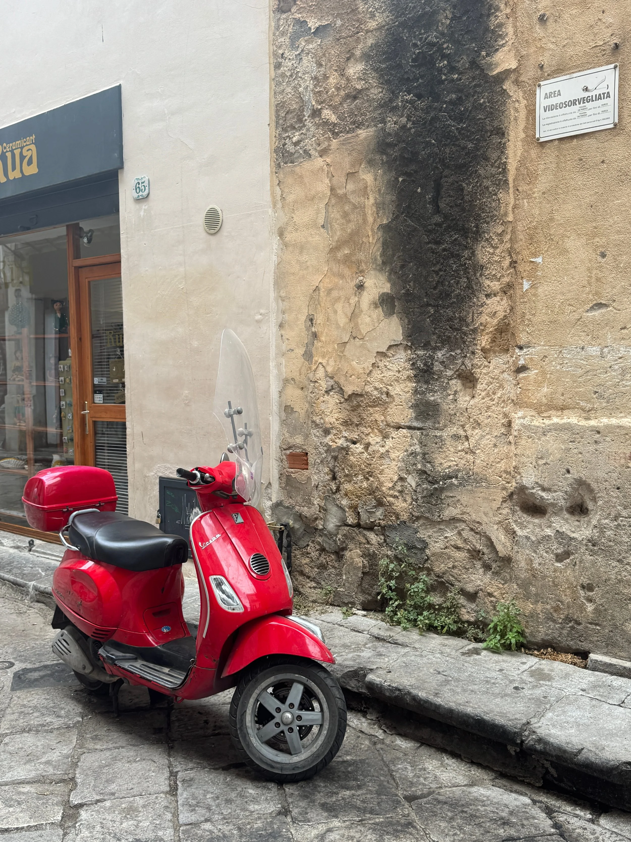 A red scooter rests on the sidewalk, showcasing its sleek design against the backdrop of the city.