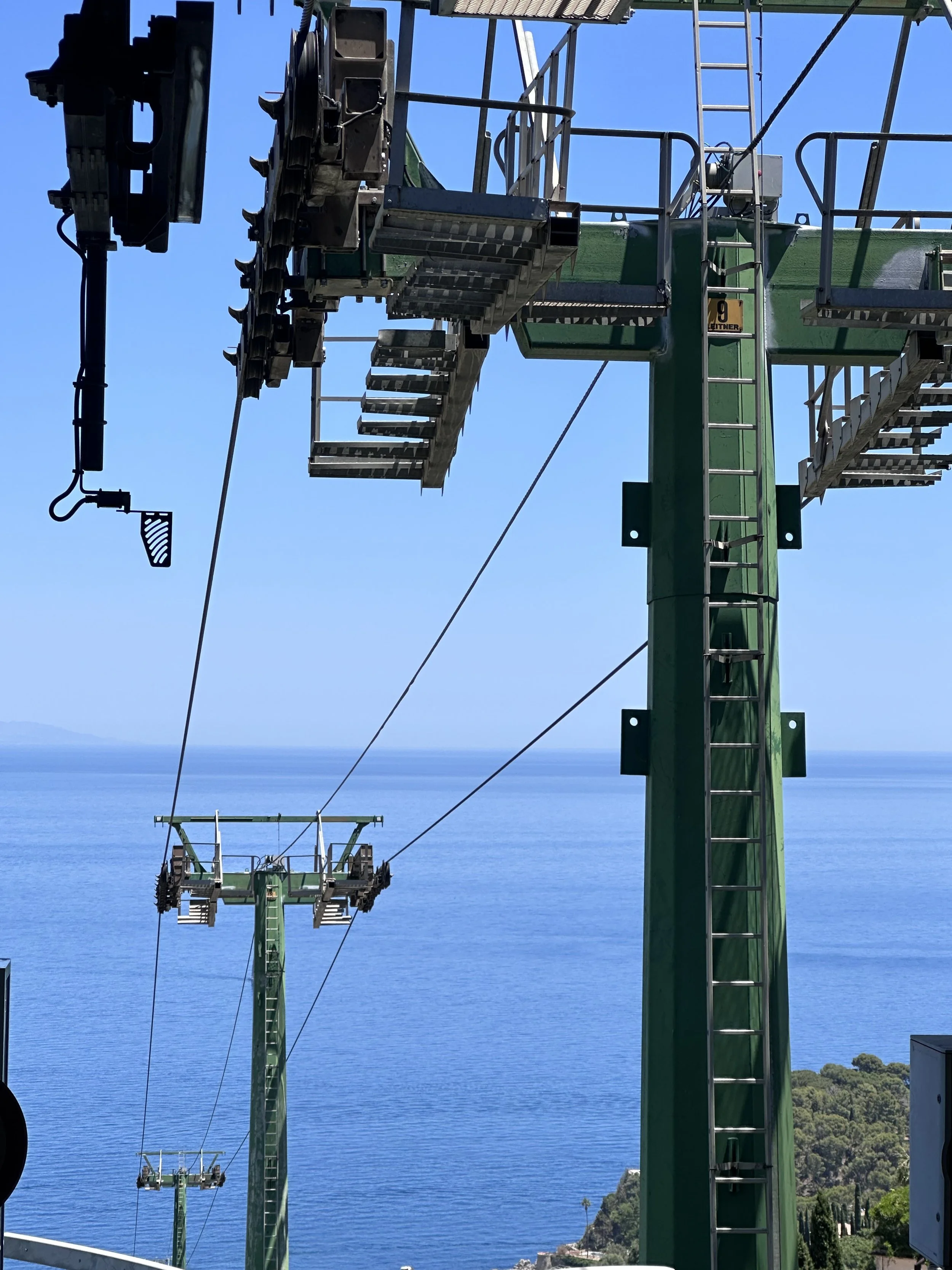 A view of a cable car with a clear blue sky and ocean in the background.