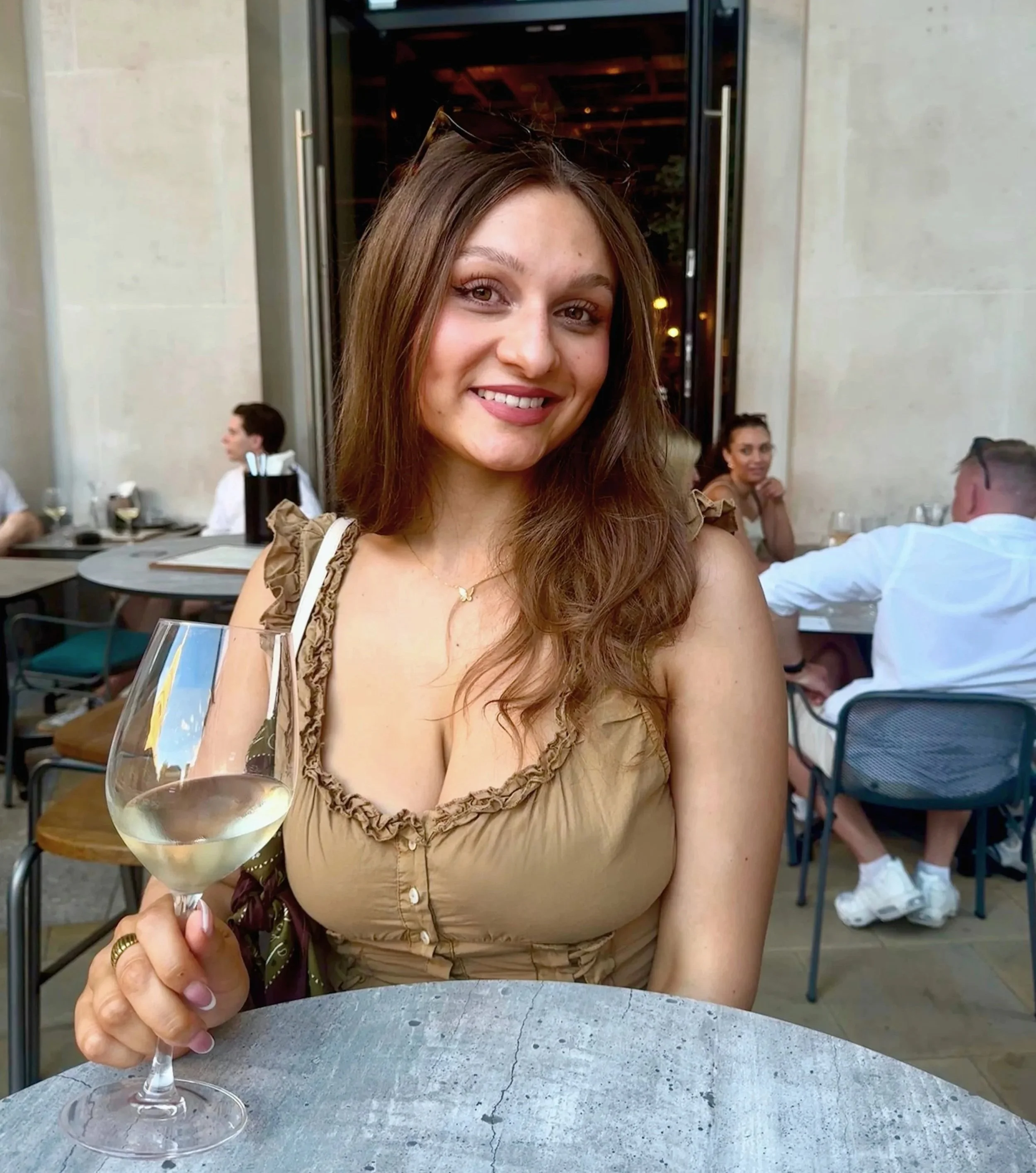 A woman elegantly holds a glass of wine, showcasing a relaxed atmosphere at Vagabond in London.