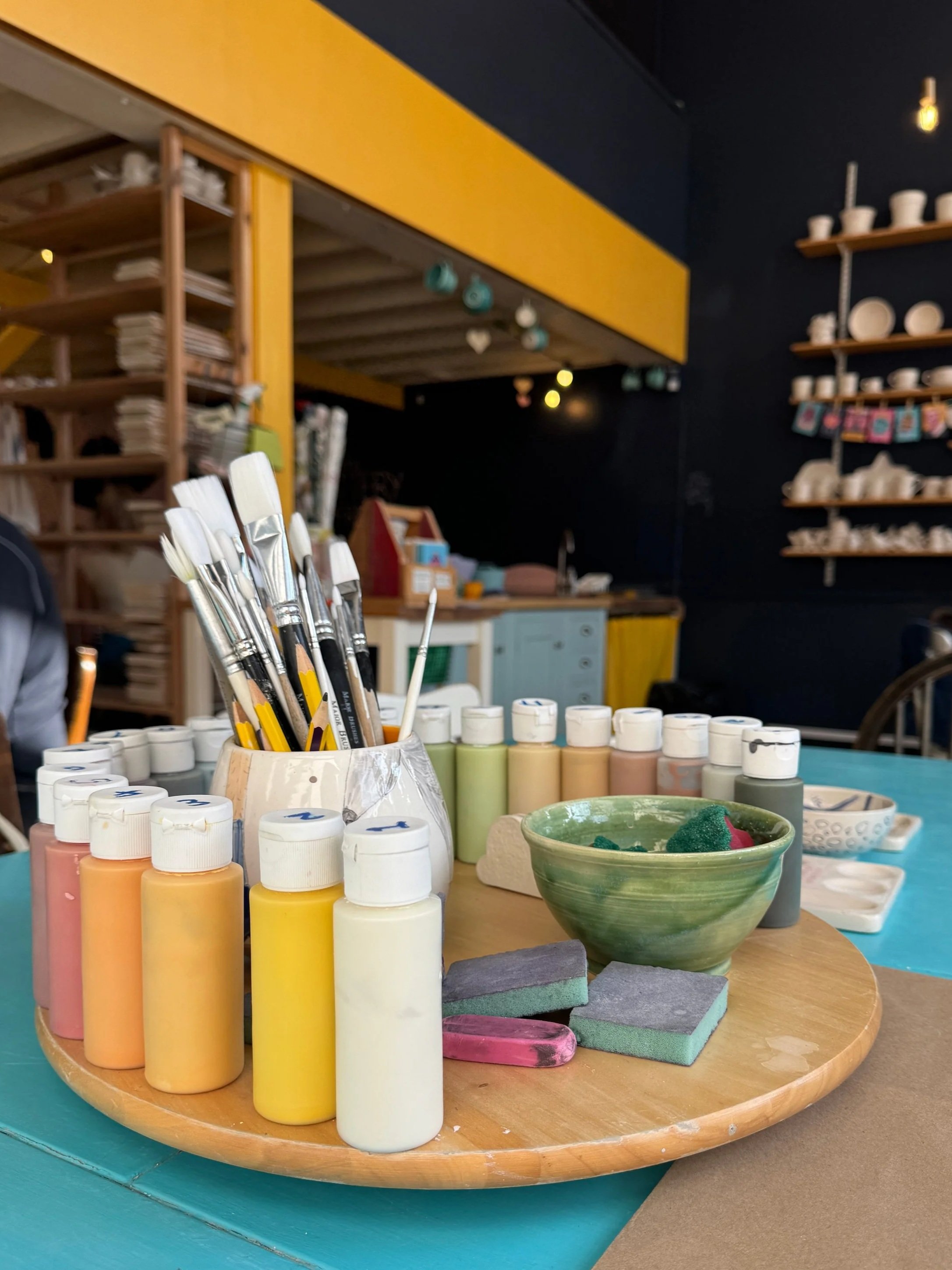 The table set up at the Pottery Experience with paints and brushes