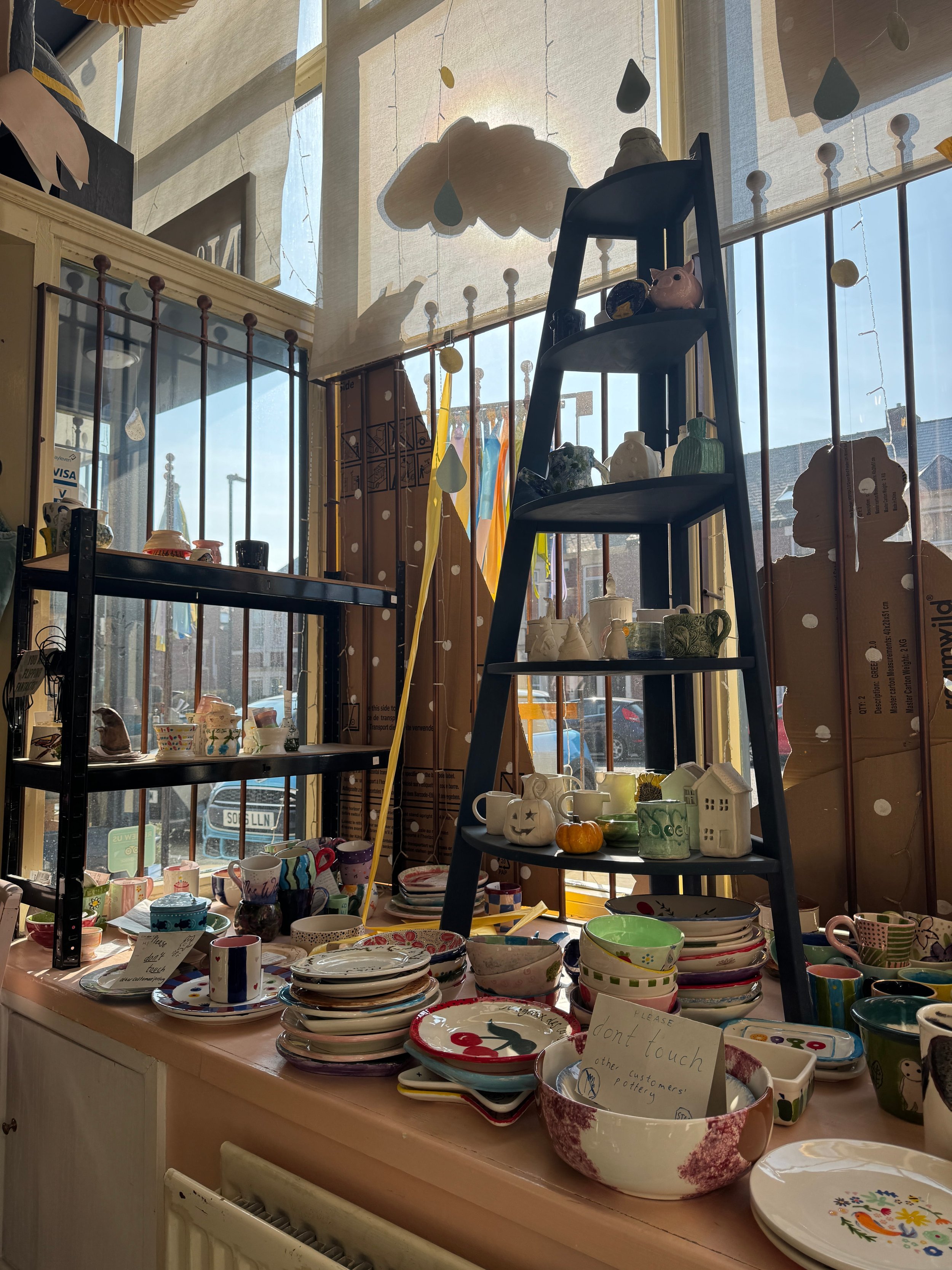 A windowsill full of creative painted pottery pieces.