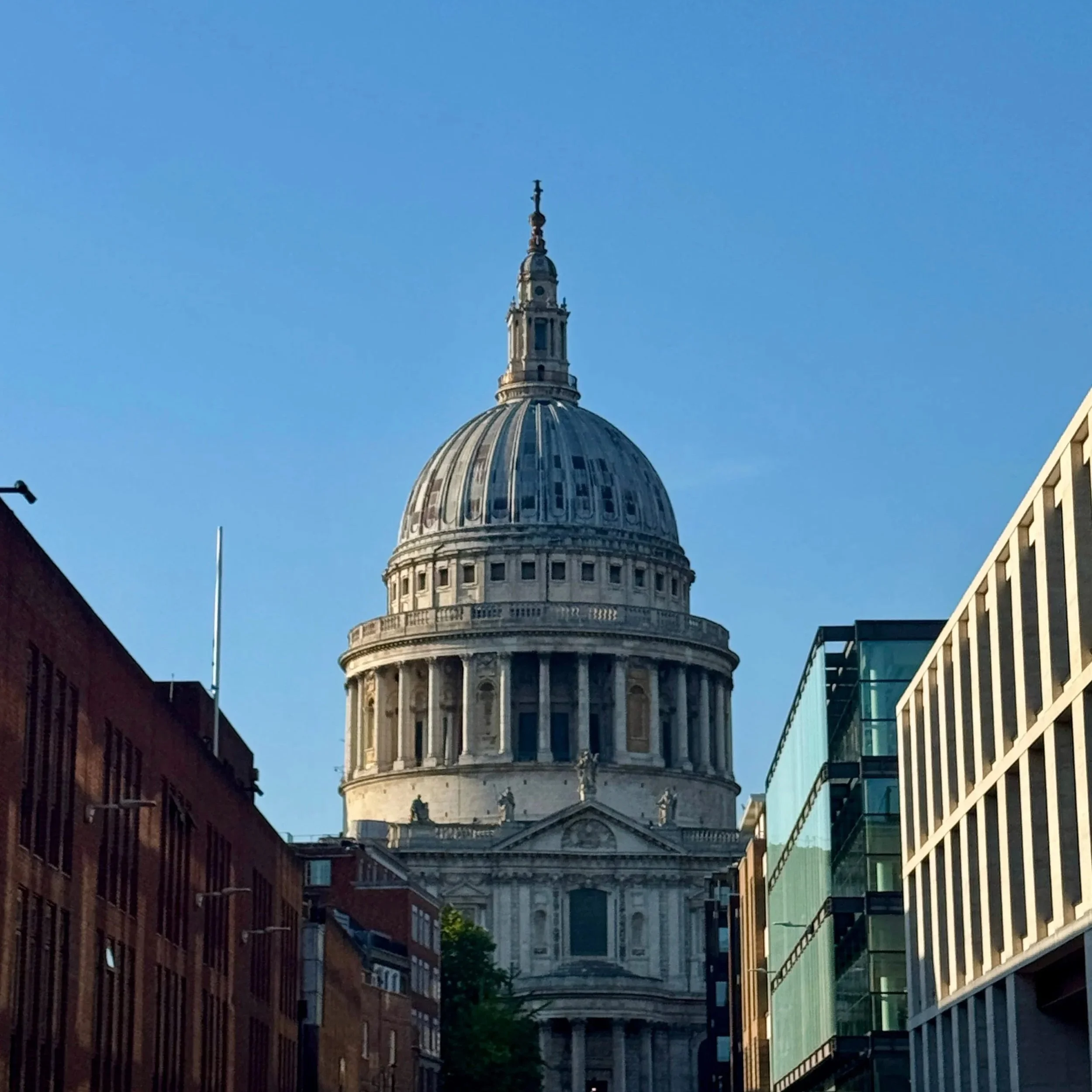 St. Paul's Cathedral in London, showcasing its iconic dome and intricate architectural details against a clear blue sky.