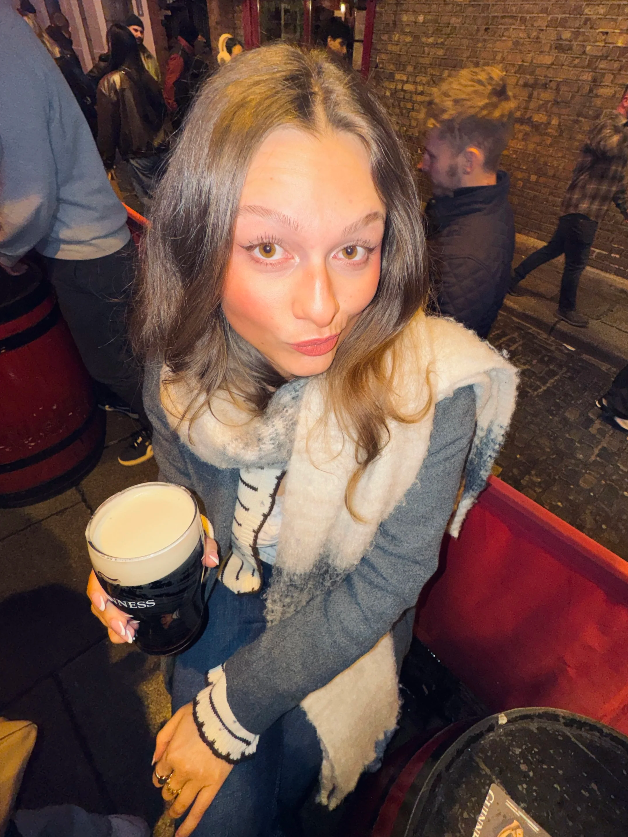 A woman posing with a pint of Guinness outside the Temple Bar in Dublin