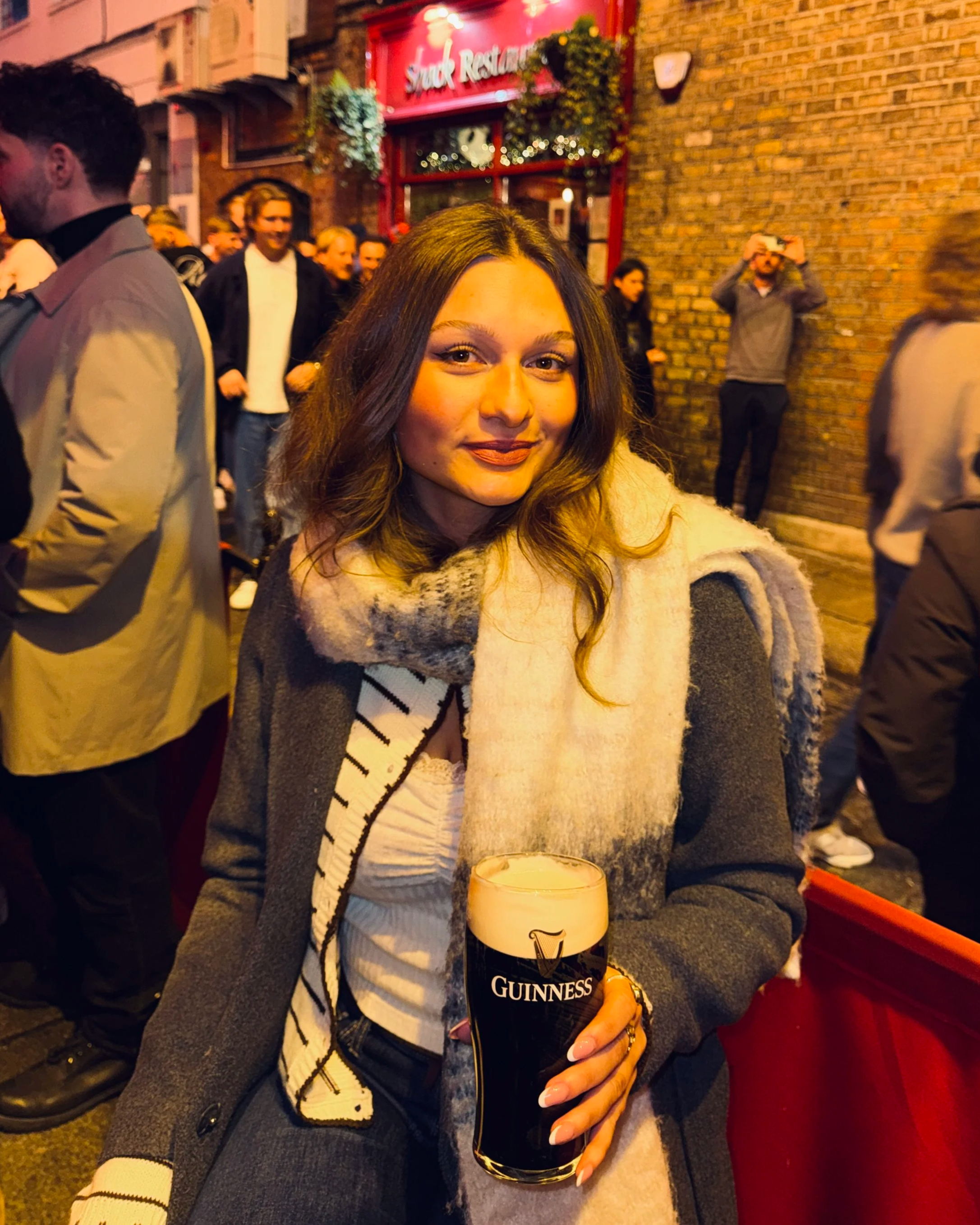 A woman sitting outside the Temple Bar and holding a pint of Guinness