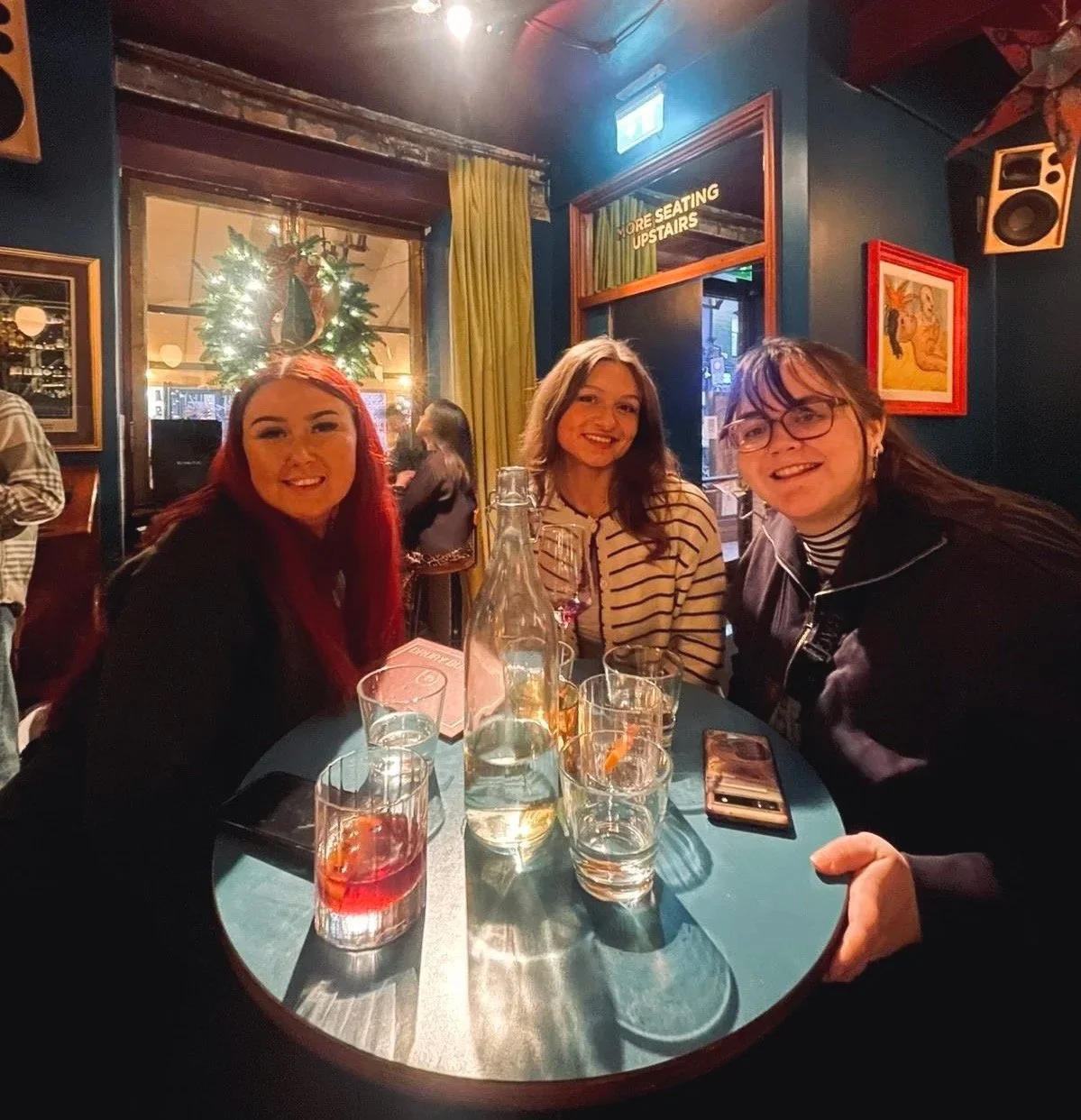 Three girls smiling round a table with drinks in a pub in Dublin