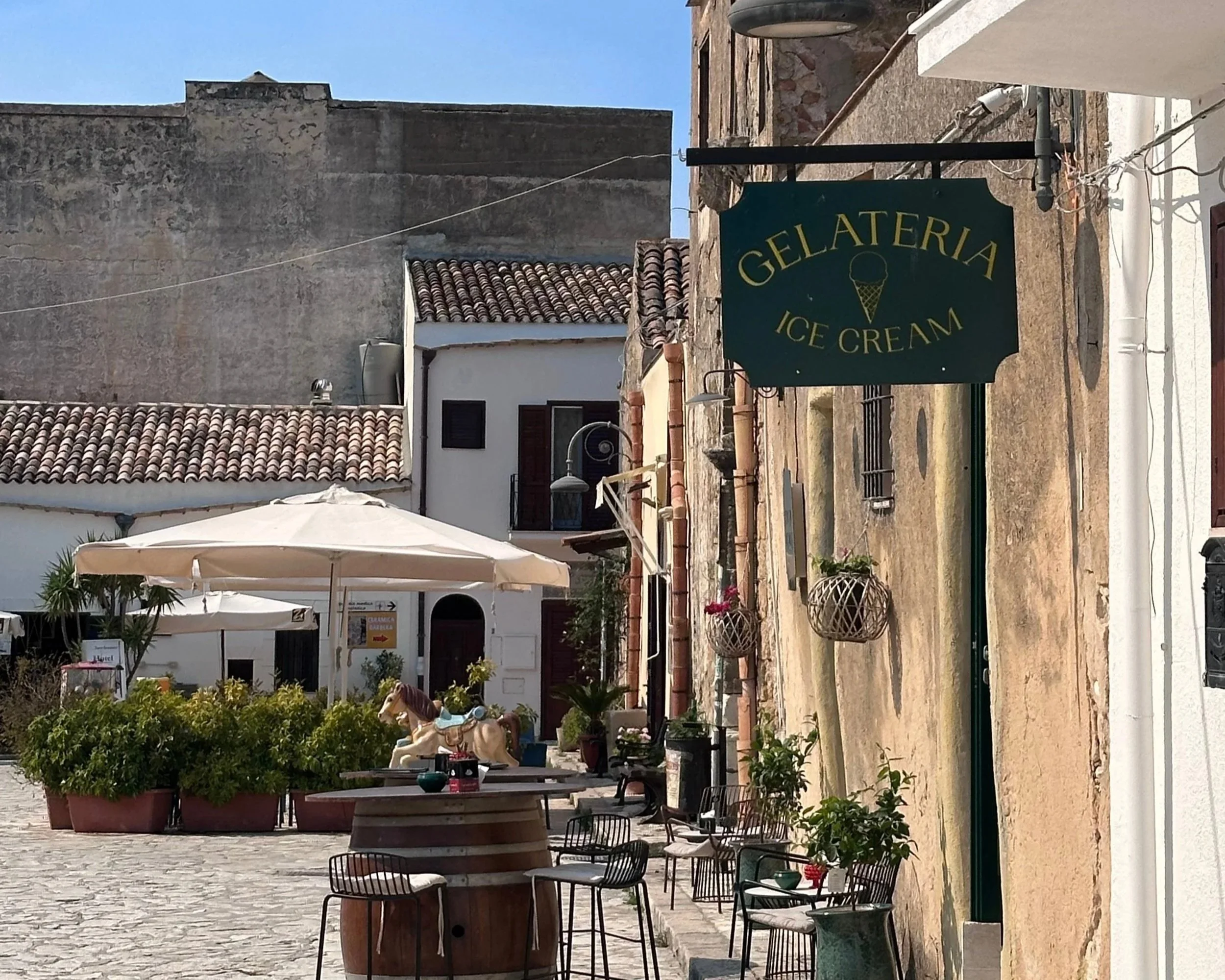 A picturesque street with a prominent sign saying "Gelateria Ice cream" in Scopello,