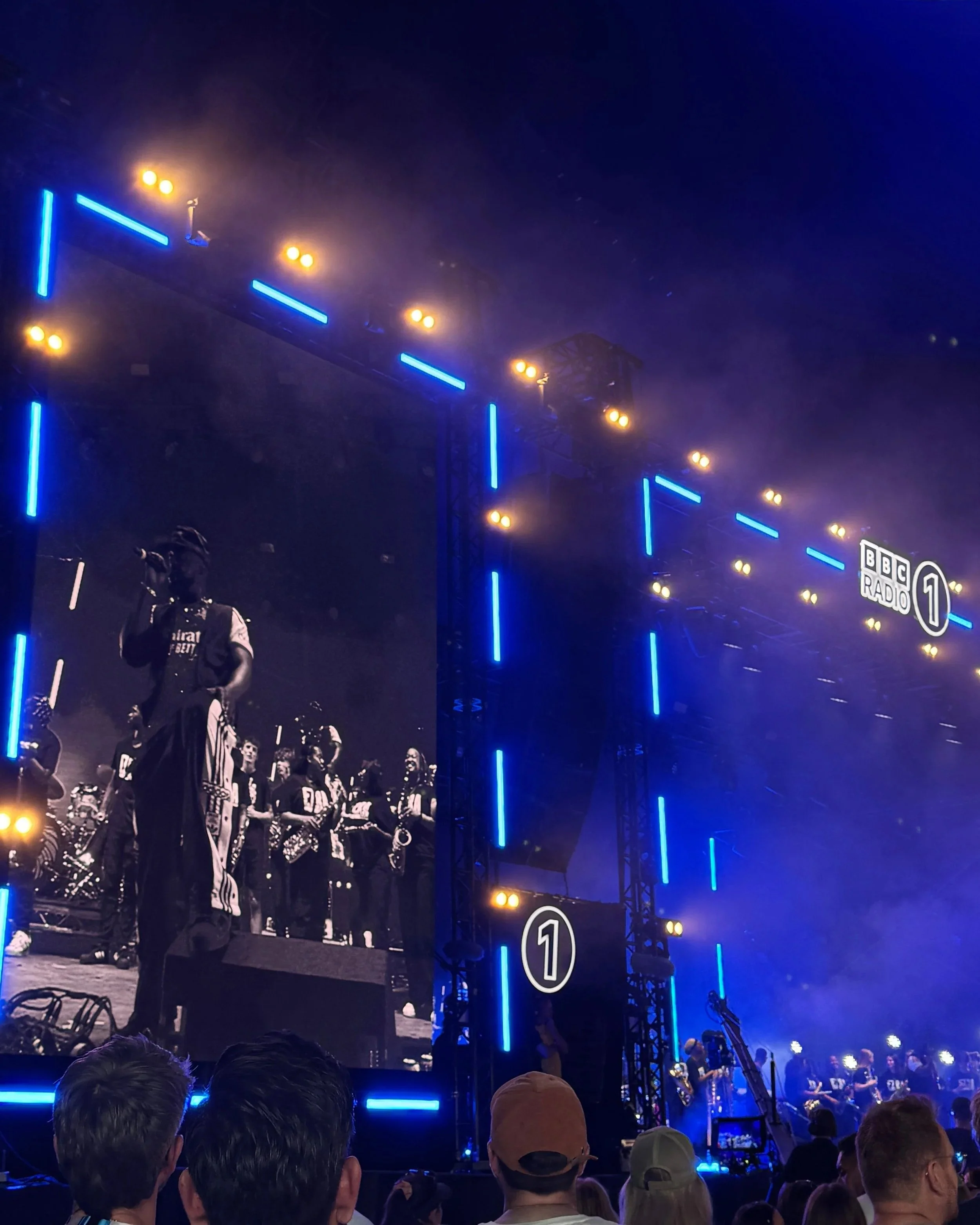 A large screen displays Ezra Collective performing on stage at night during the BBC Radio 1 Weekend in Sunderland.