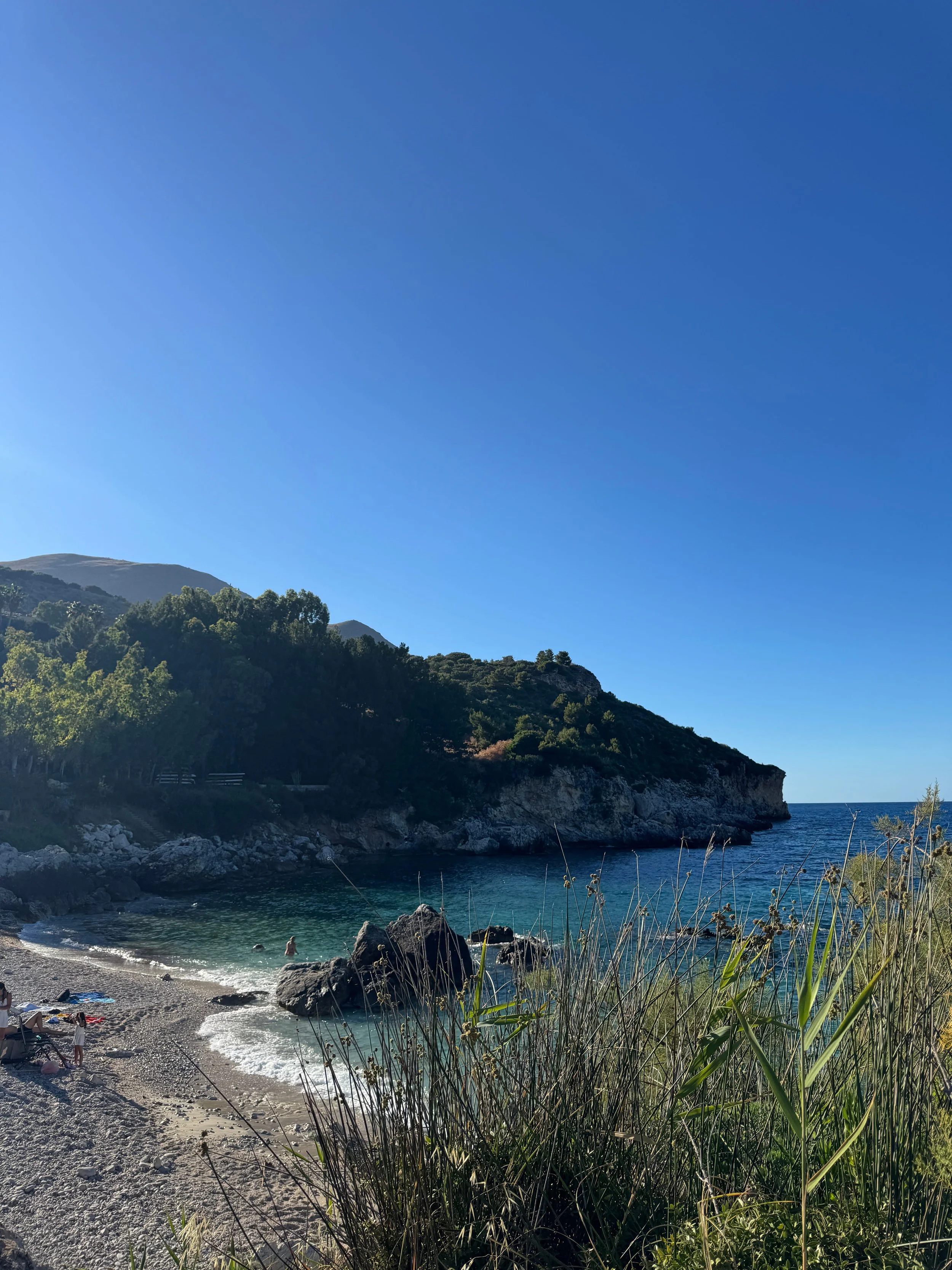 A serene beach scene featuring soft sand and a clear blue sky, perfect for relaxation and sunbathing.
