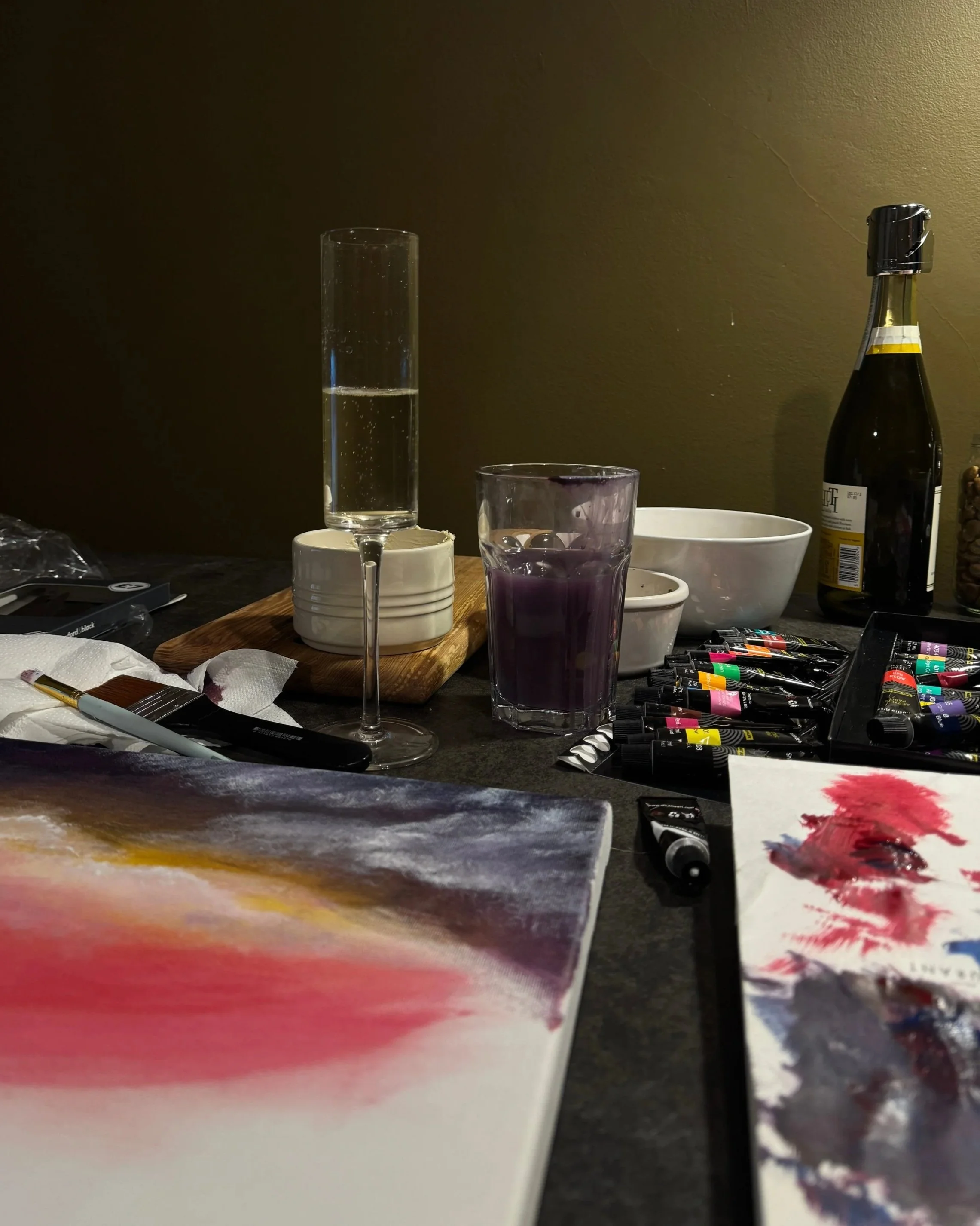 Art supplies and a bottle of prosecco on a table