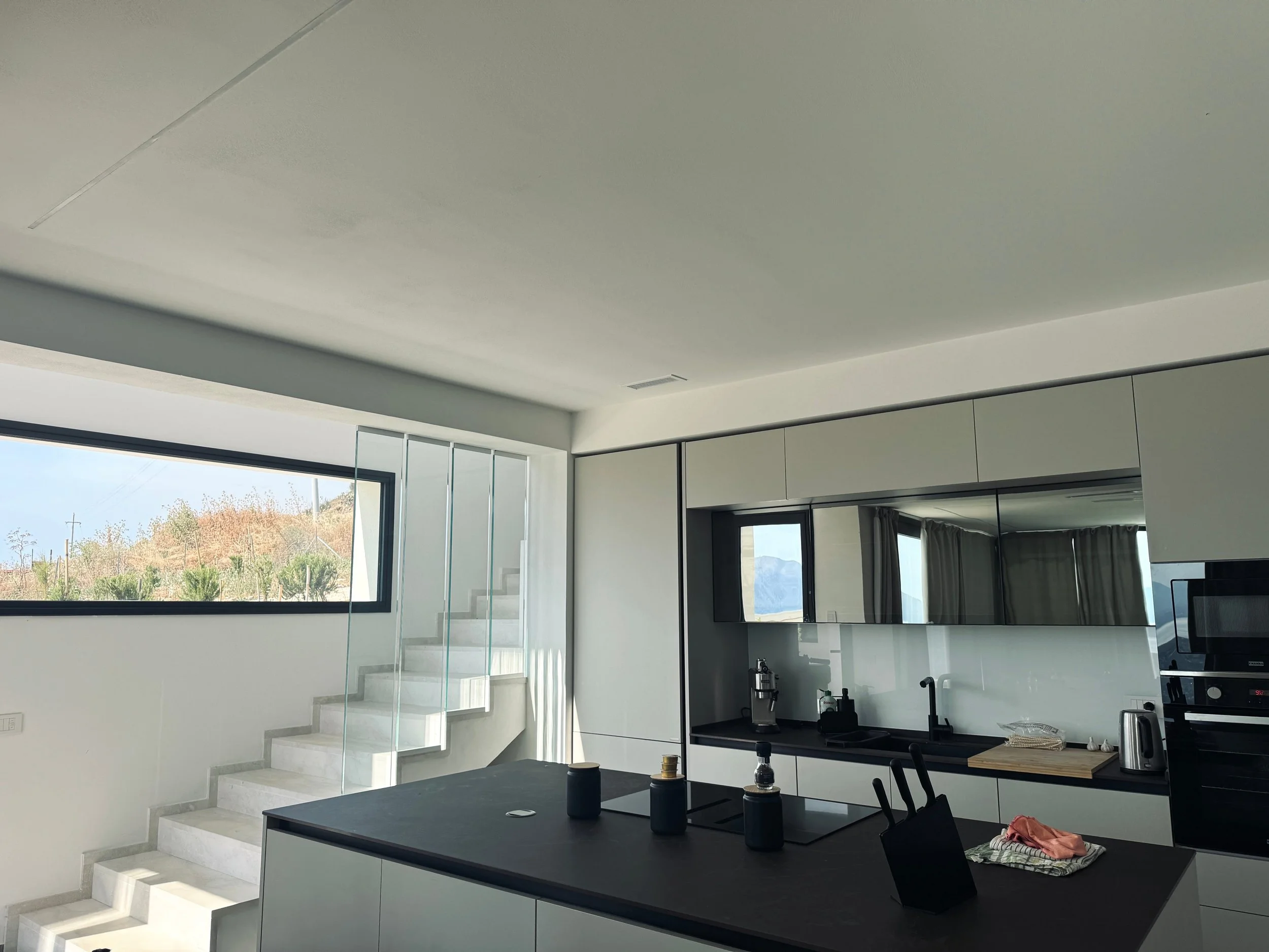 Spacious kitchen with a large window letting in natural light, complemented by a staircase leading to an upper level.