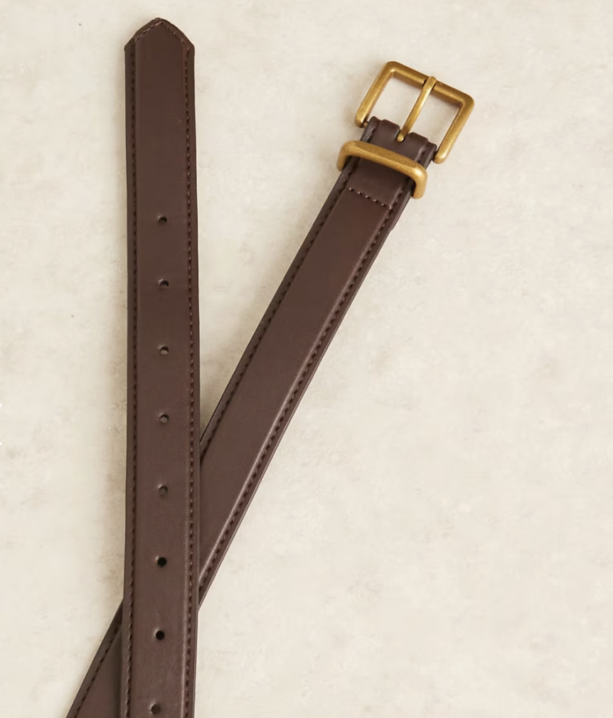 Brown leather belt with adjustable holes and a gold buckle, set against a light beige background. The tone is classic and sophisticated.