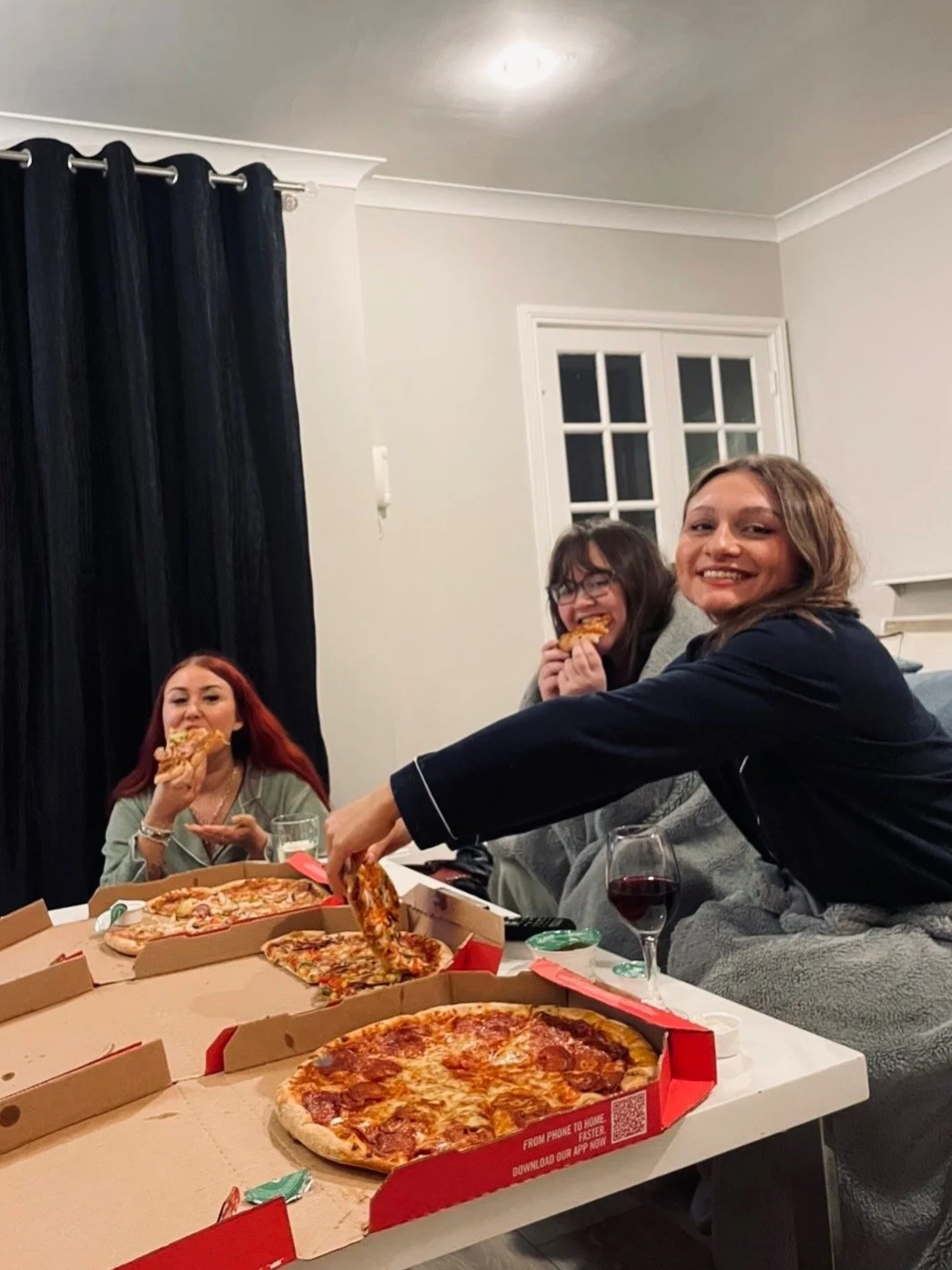 Three girls posing with a slice of pizza in their pyjamas