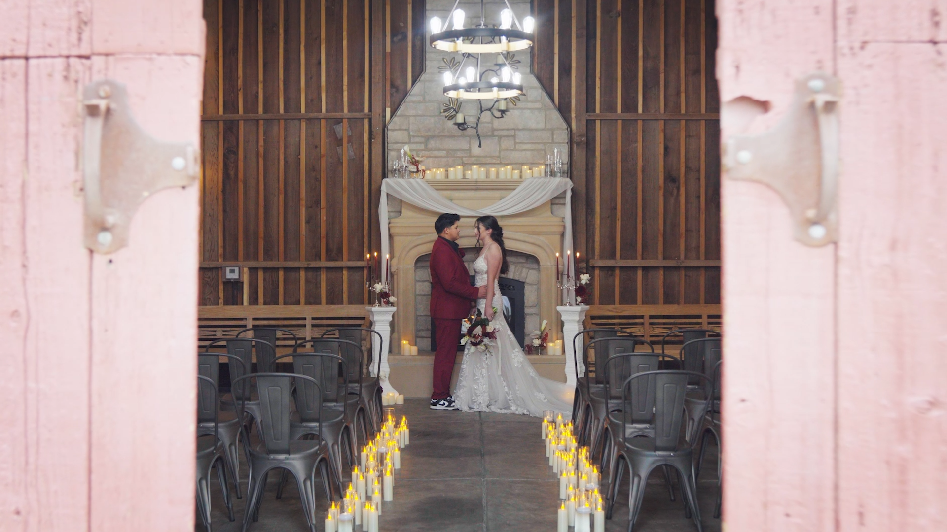 A bride and groom standing face to face in front of a fireplace decorated for a wedding ceremony.