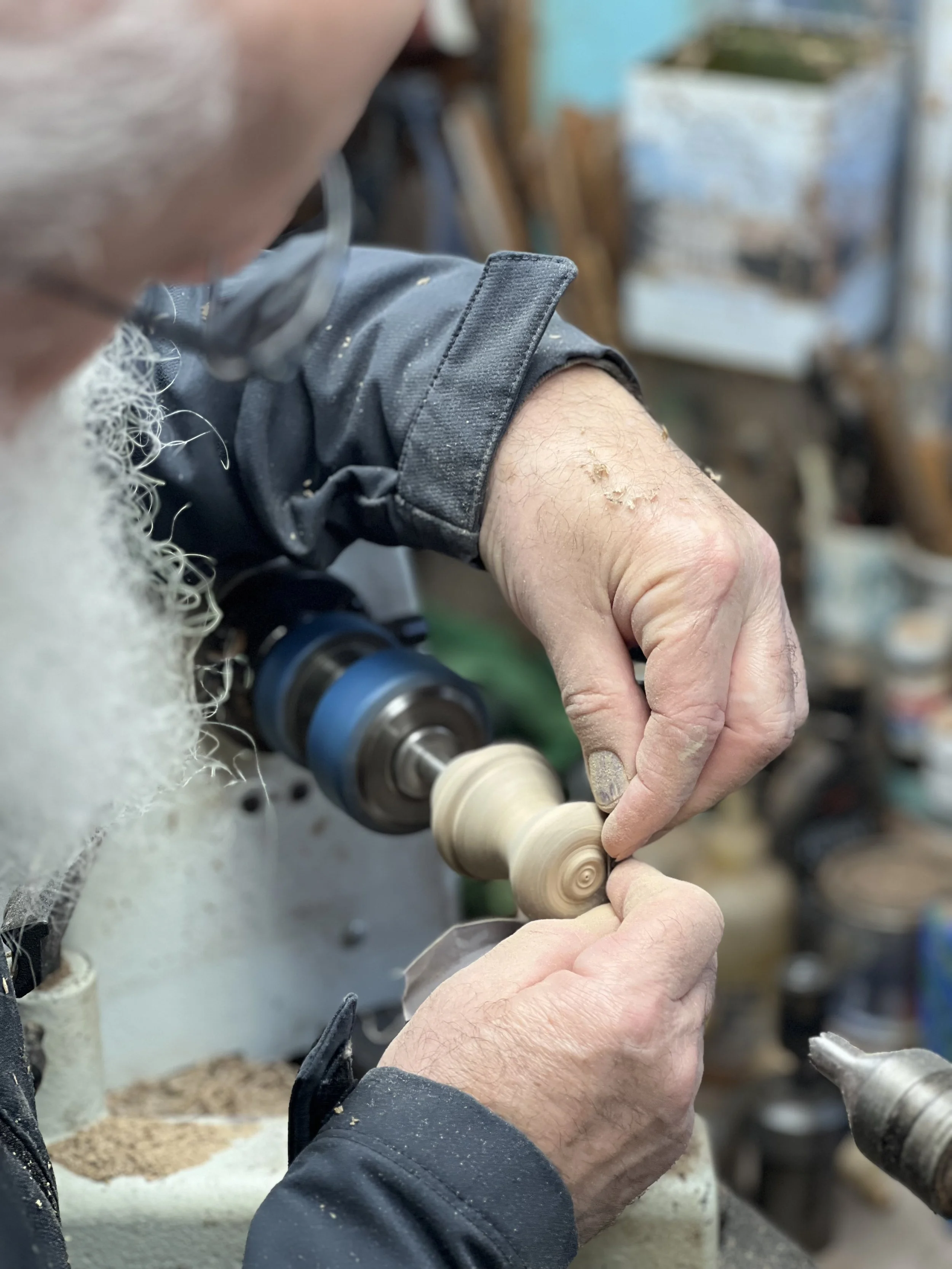 Sanding a wine bottle stopper on the lathe.
