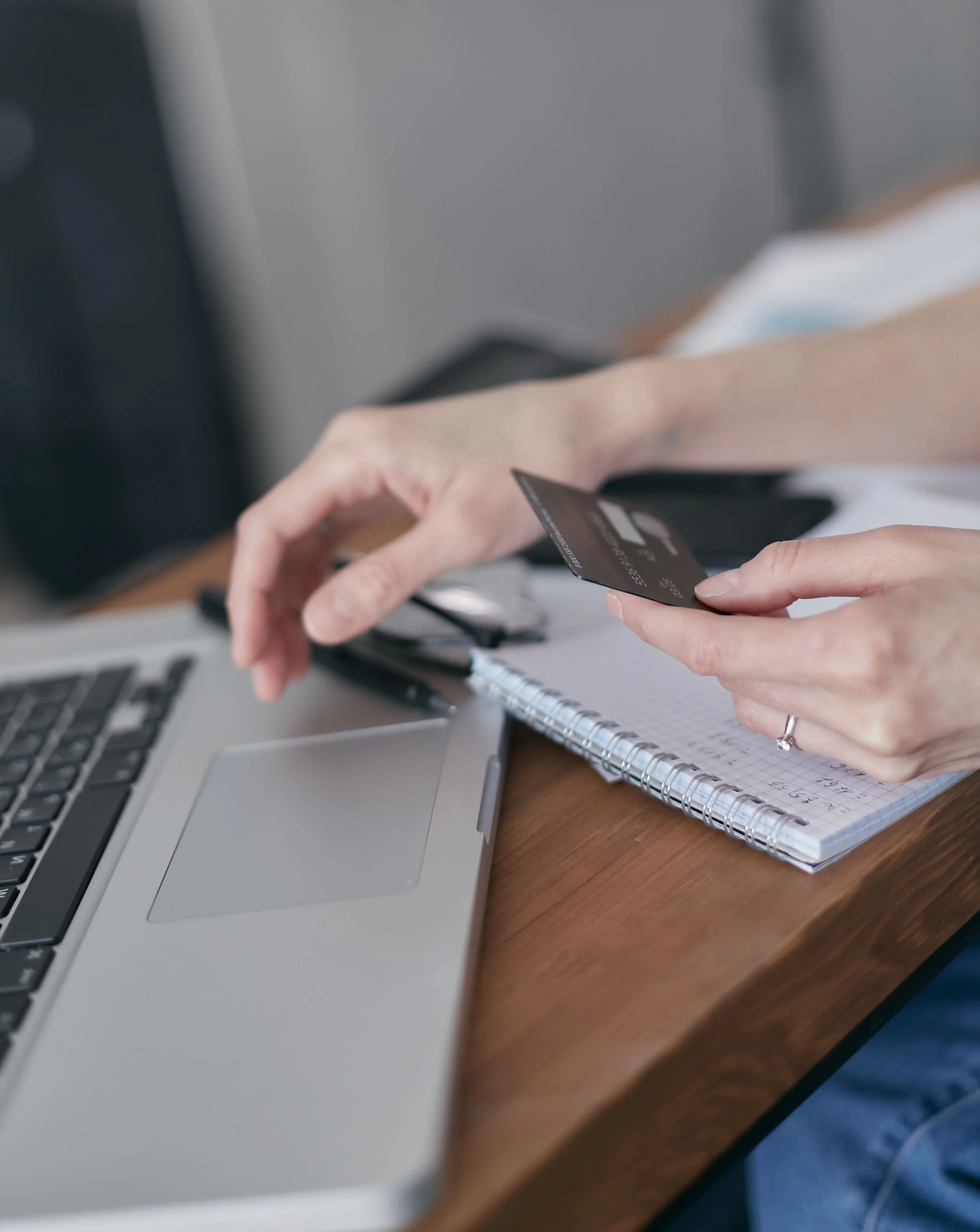 A business owner reviewing bills and payments on a laptop with a credit card, managing accounts payable for their product brand.