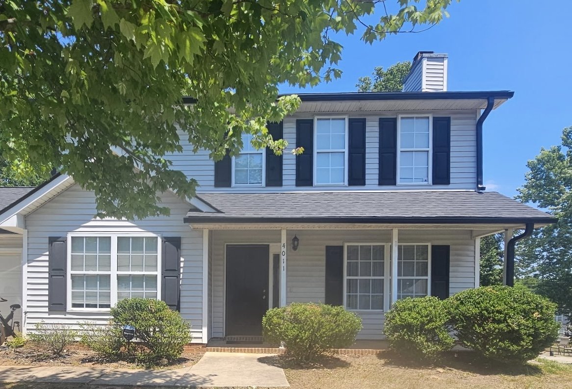 New black seamless gutters and downspouts installed on a two-story residential home by Bear Roofing LLC.