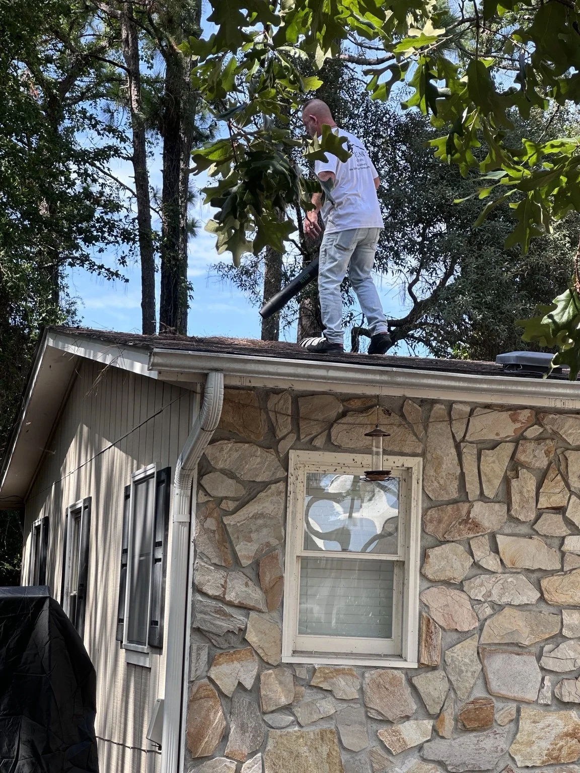 Bobby with Bear Roofing LLC using a leaf blower to remove loose debris from a residential roof.